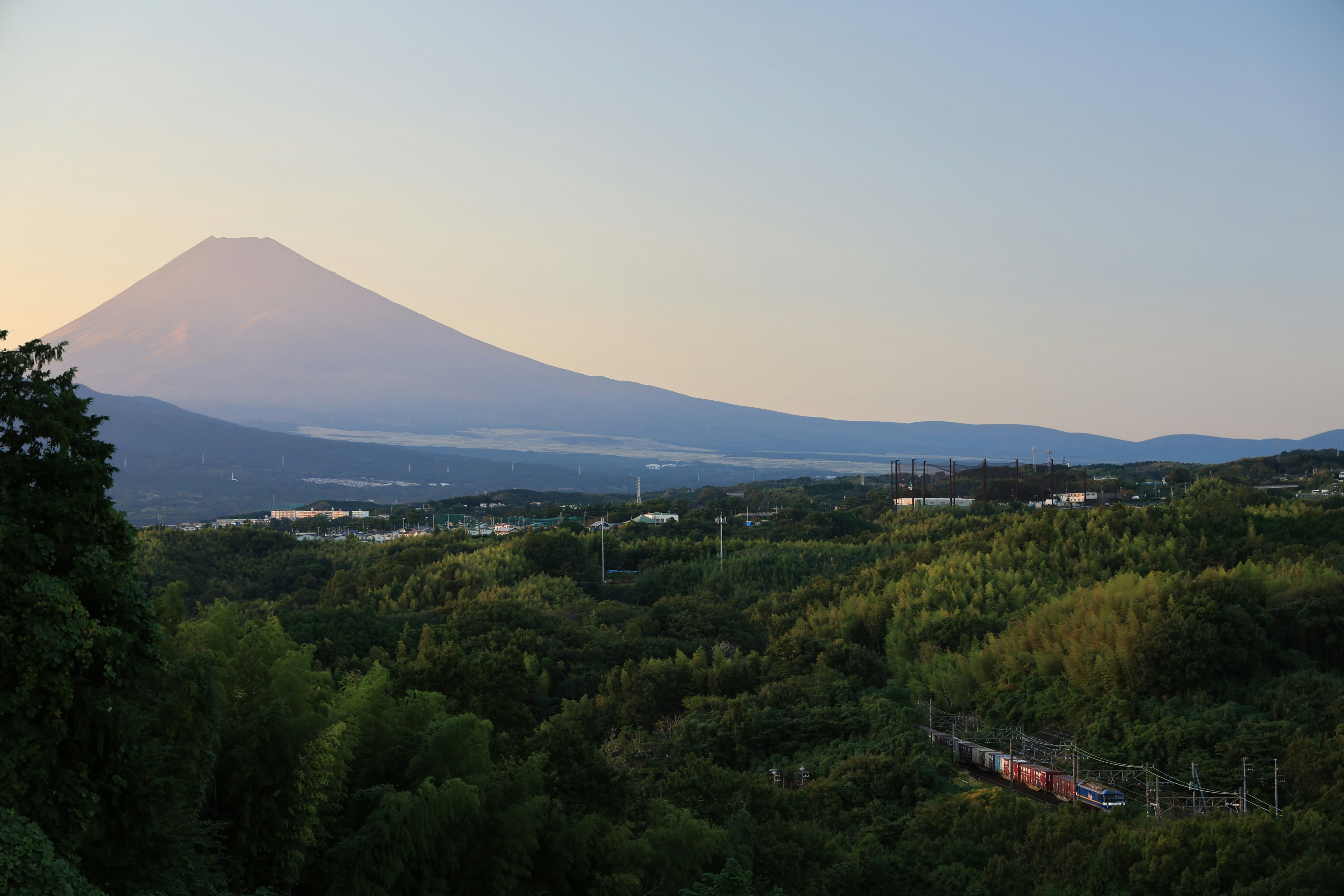 富士山の美しい夕暮れの風景 緑豊かな丘と鉄道が見える