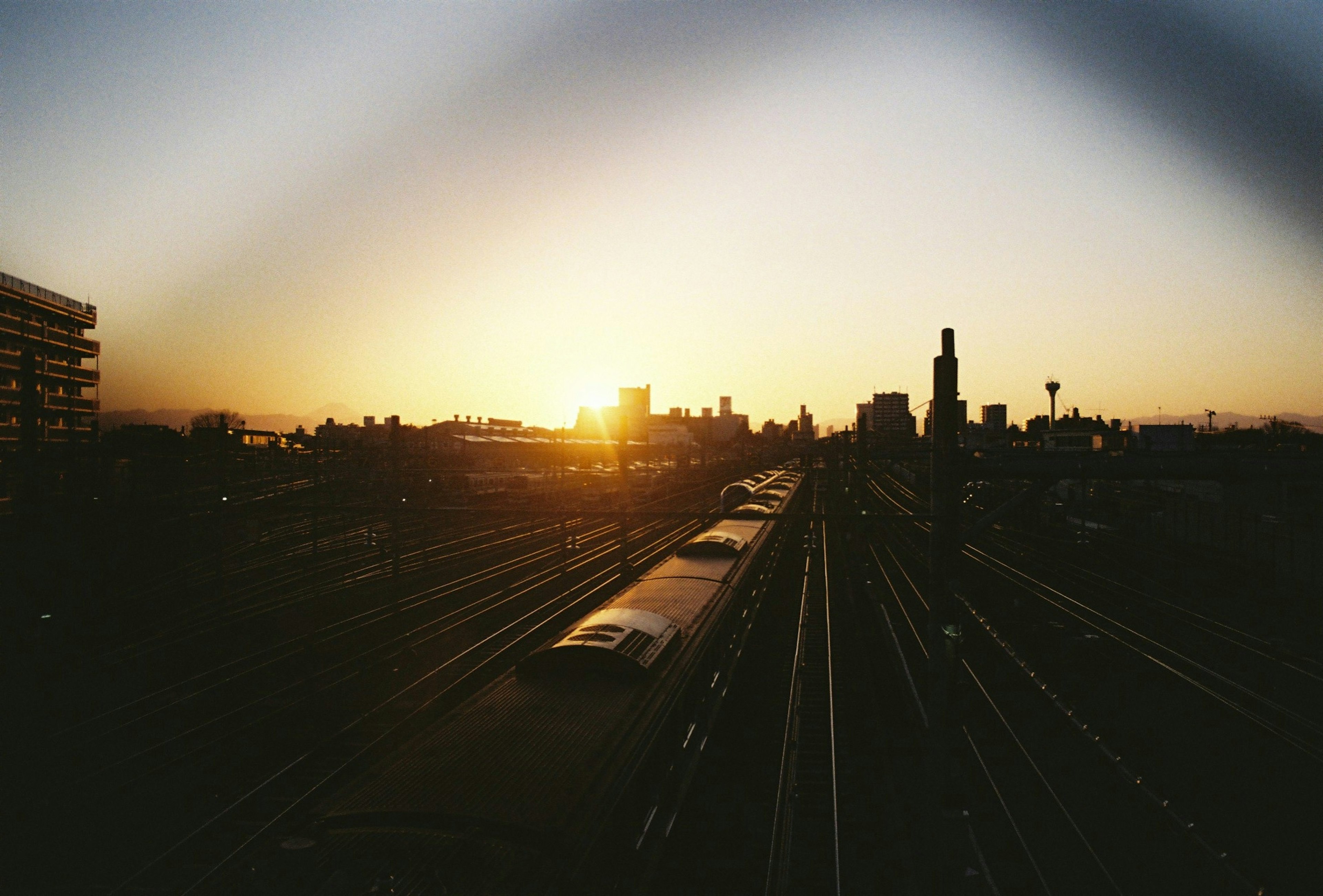 Cityscape at sunset featuring train tracks and buildings