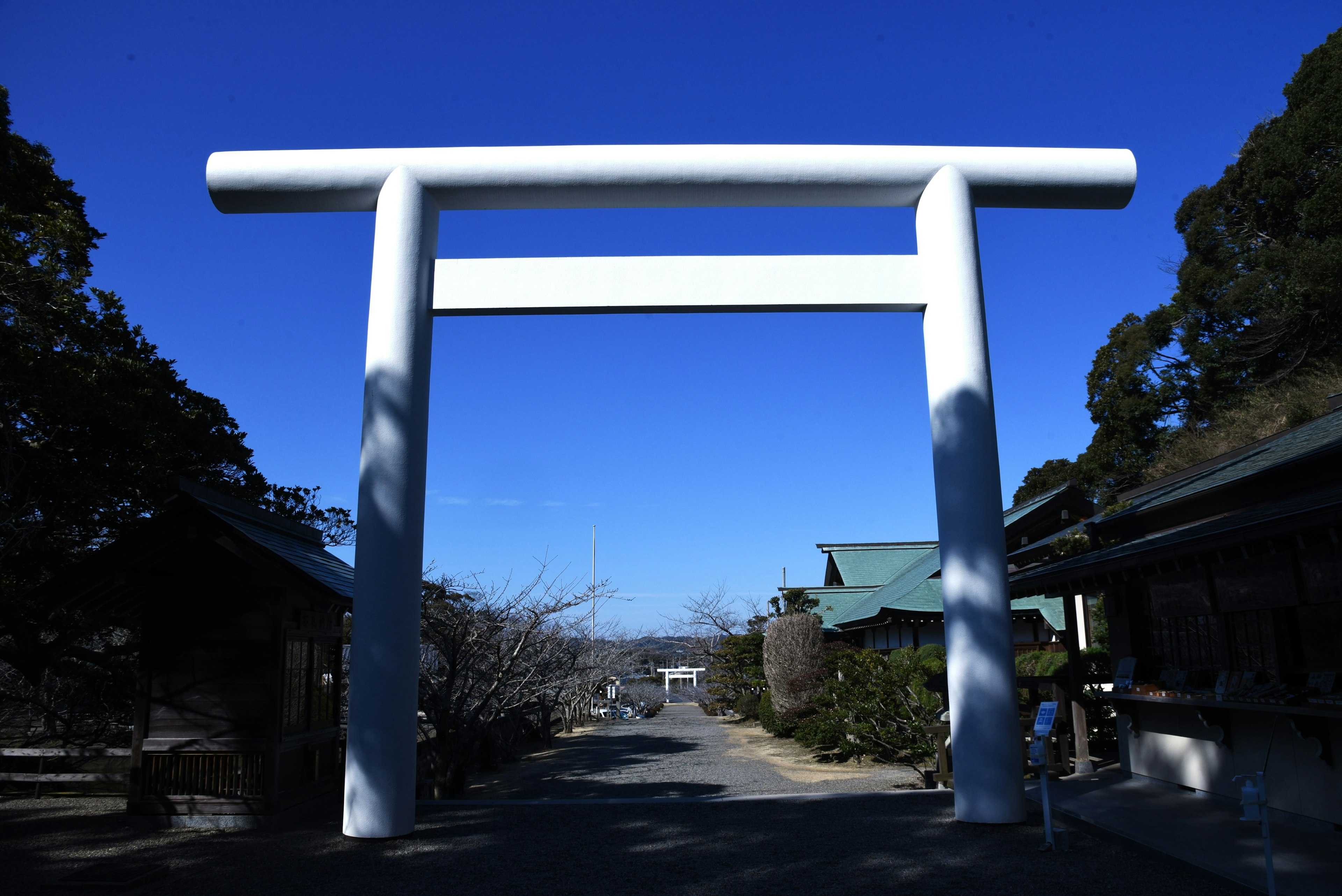 Puerta torii blanca bajo un cielo azul claro en un santuario