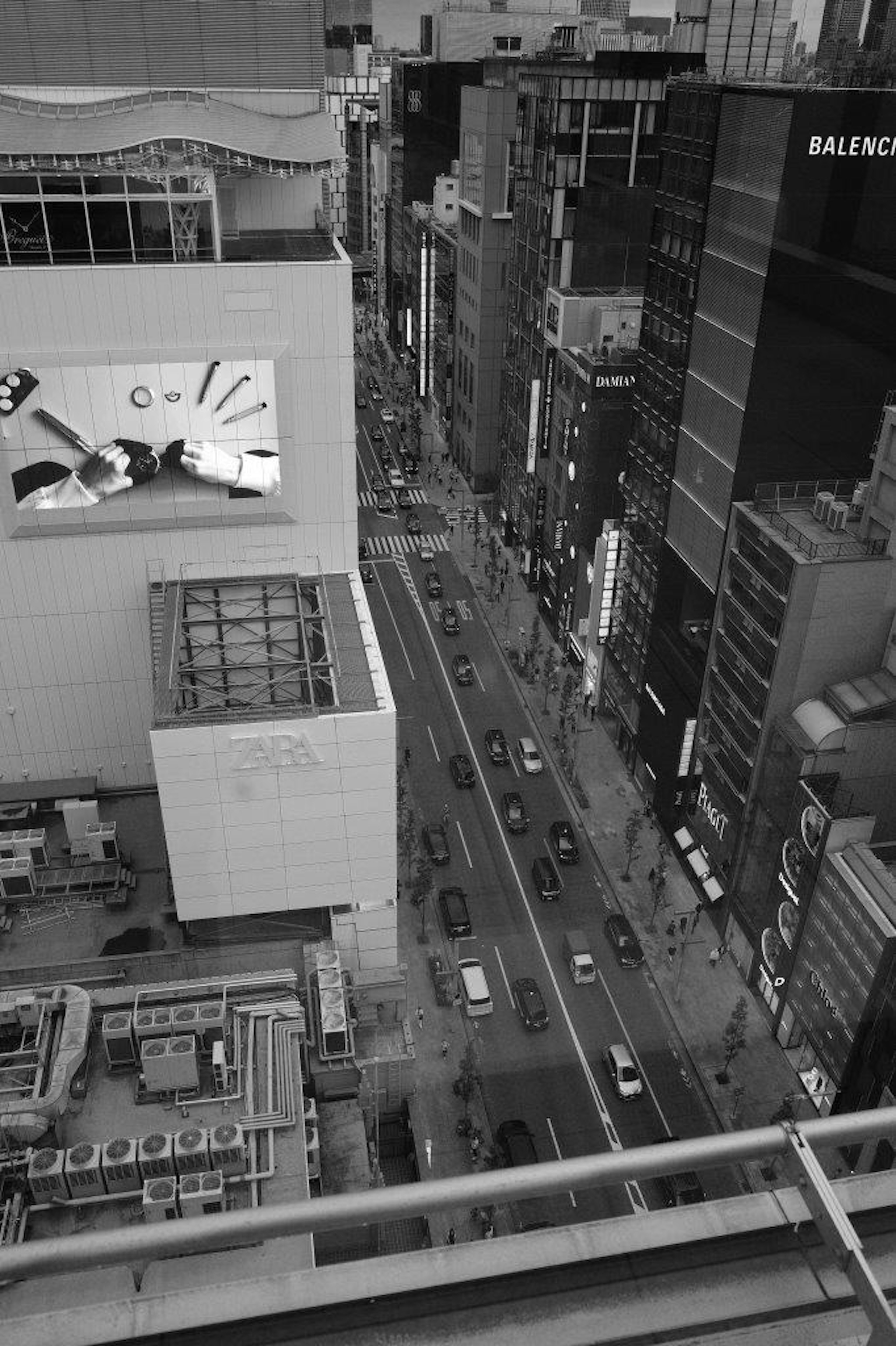 高層ビルの間から見下ろした都市の風景 道路と車が見える