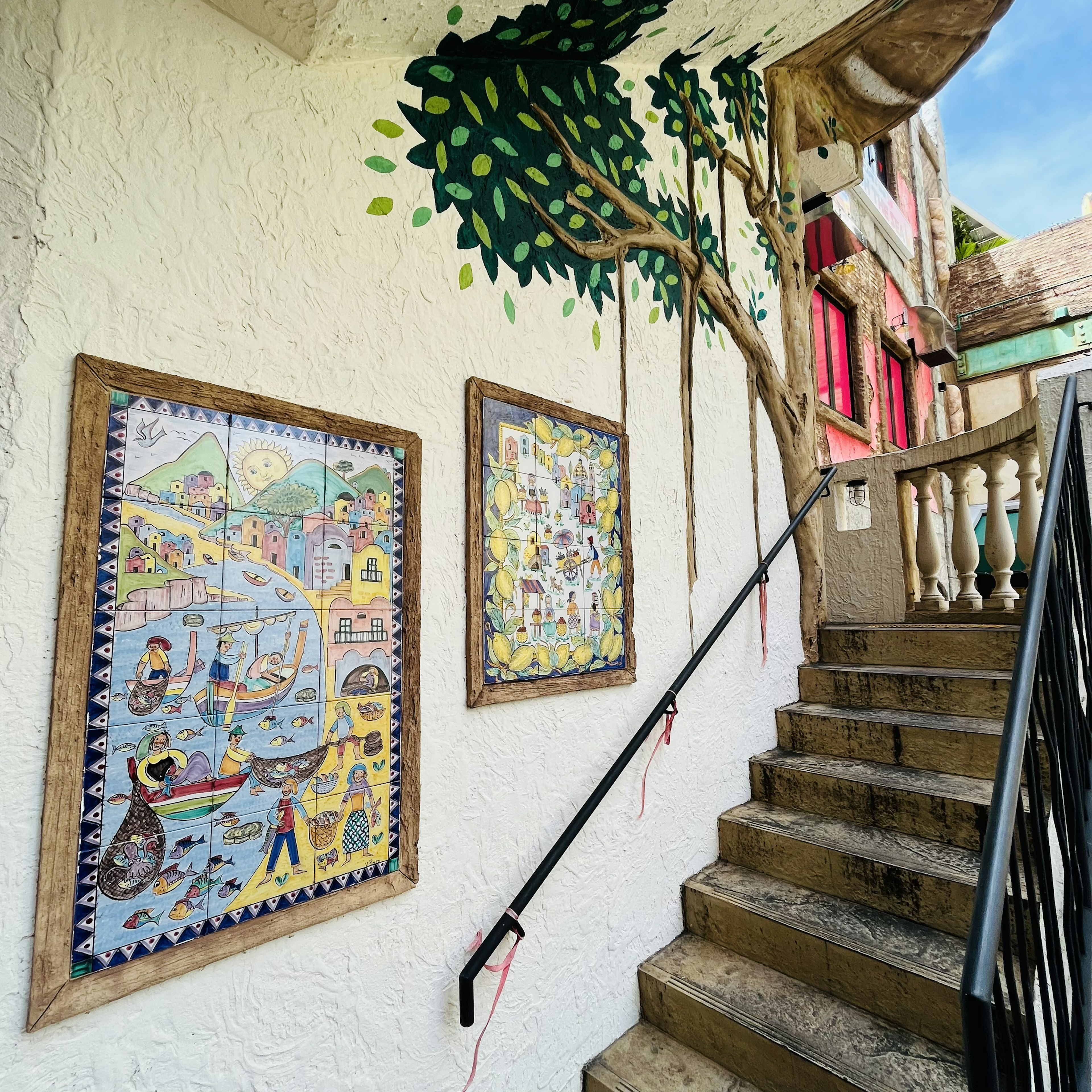 Art en carreaux colorés et design d'arbre mural le long de l'escalier