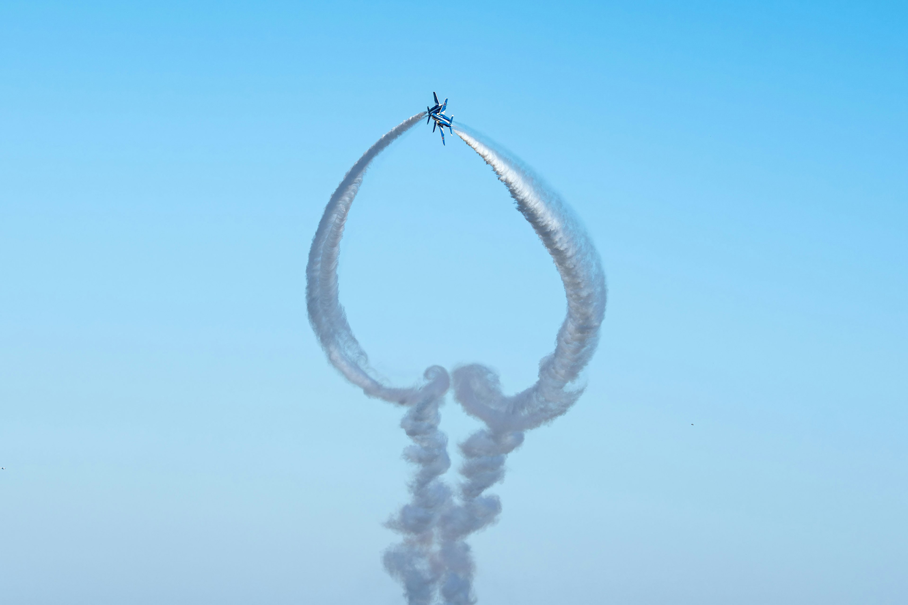 Un avion volant dans le ciel bleu créant une belle traînée de fumée circulaire