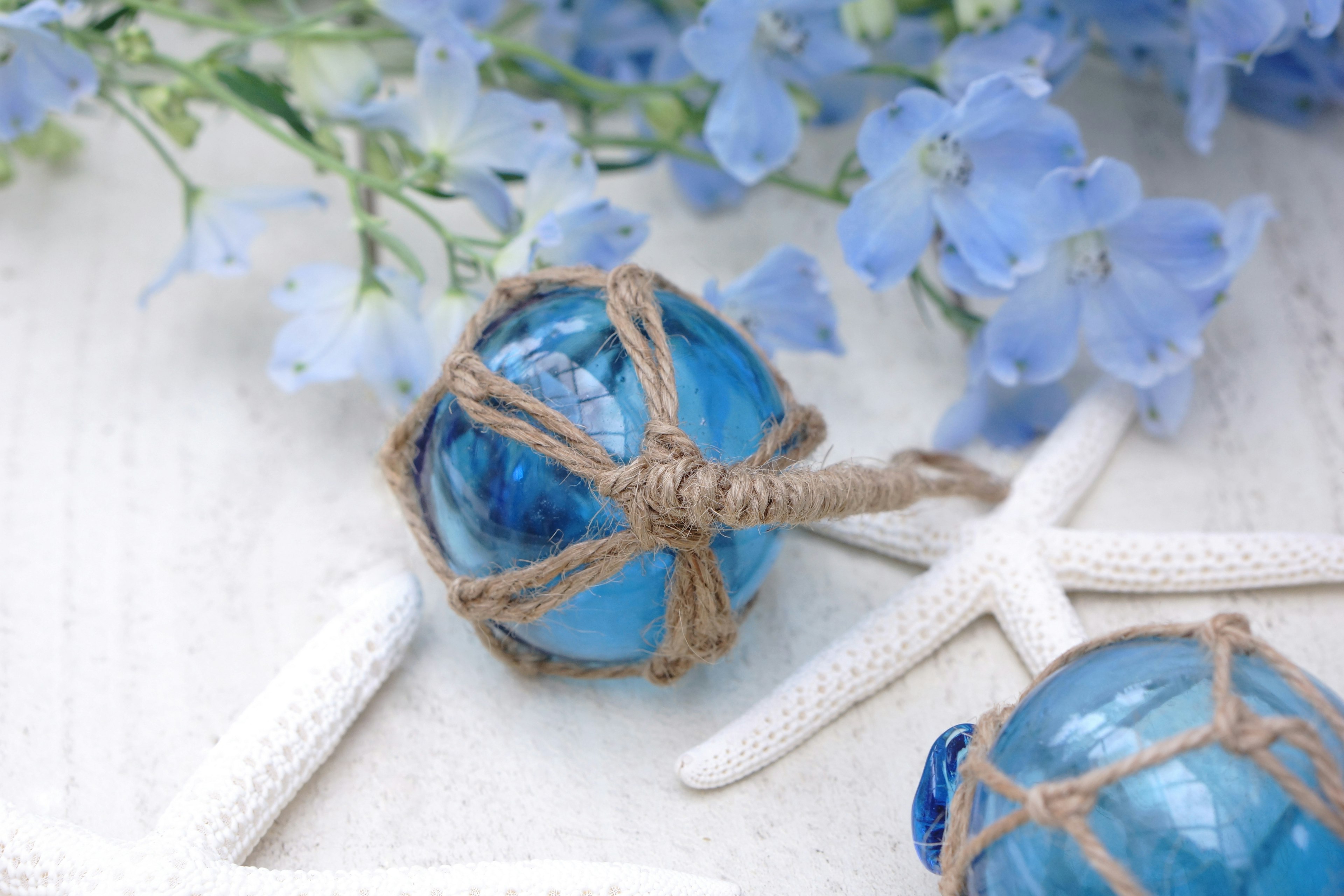 Blue glass orbs tied with twine surrounded by starfish and blue flowers