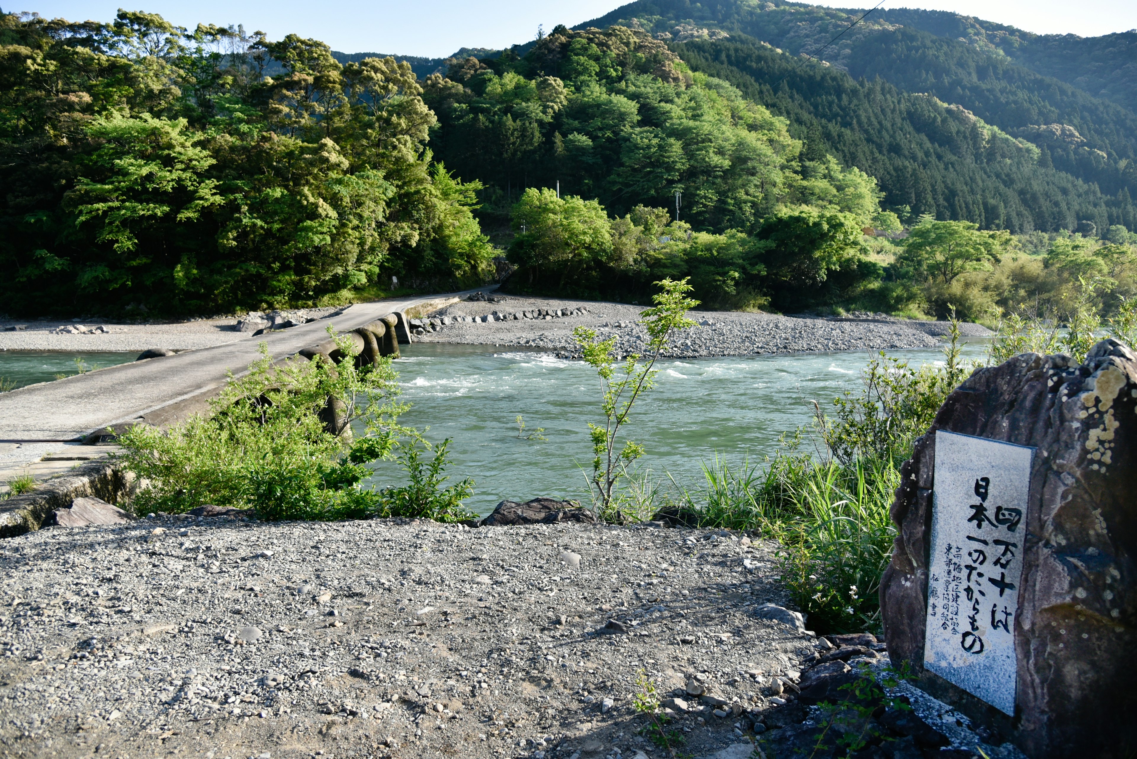 Vista escénica de un río rodeado de vegetación y un puente con piedra grabada