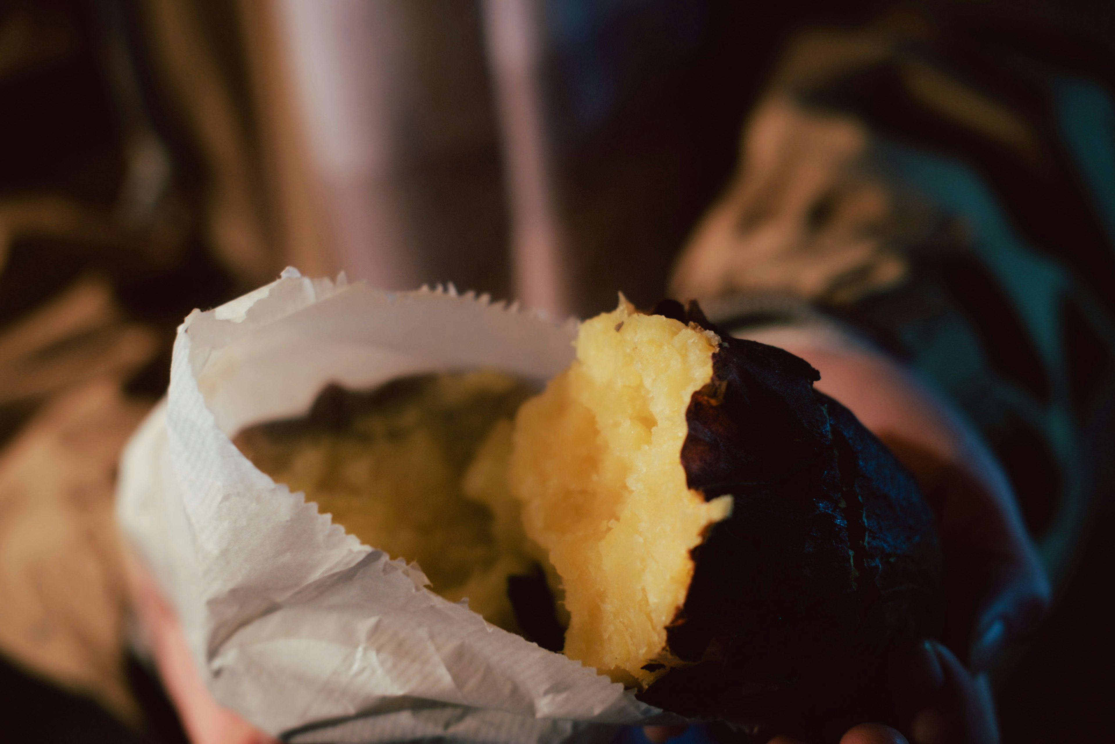 Close-up of a hand holding a baked sweet potato