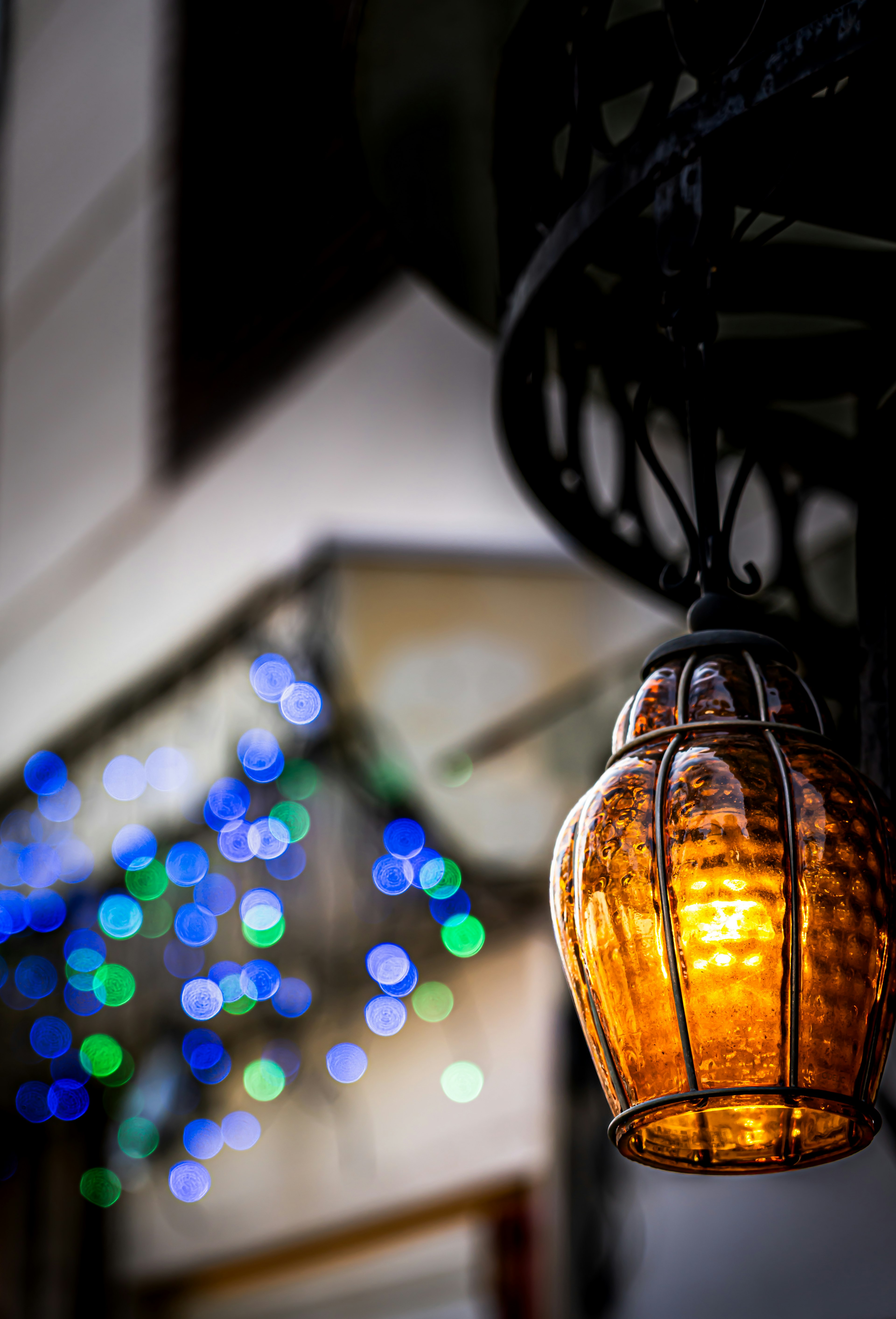 Hanging orange lantern illuminated at night with colorful lights in the background