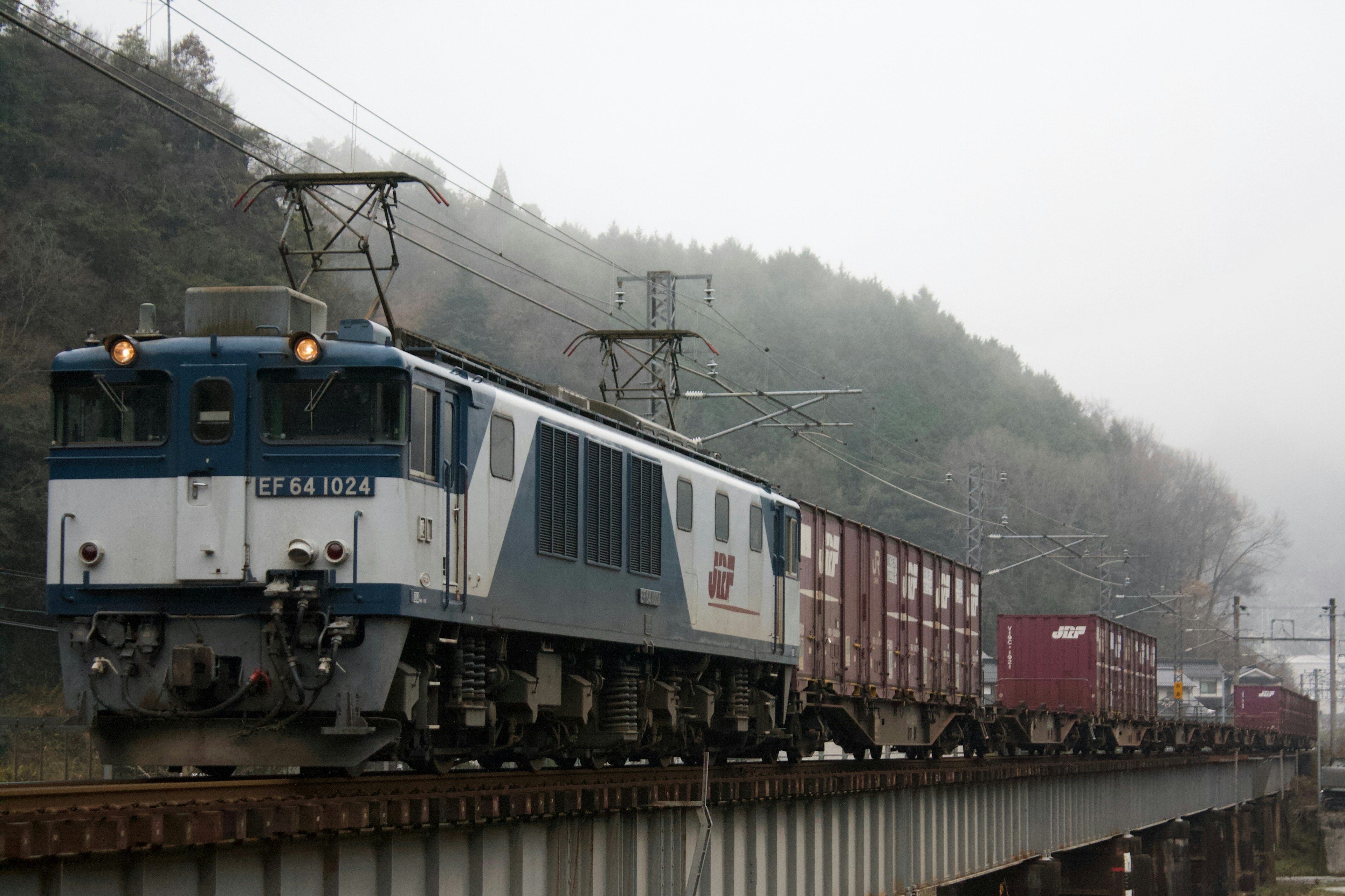 霧の中を走る貨物列車とその周囲の山々