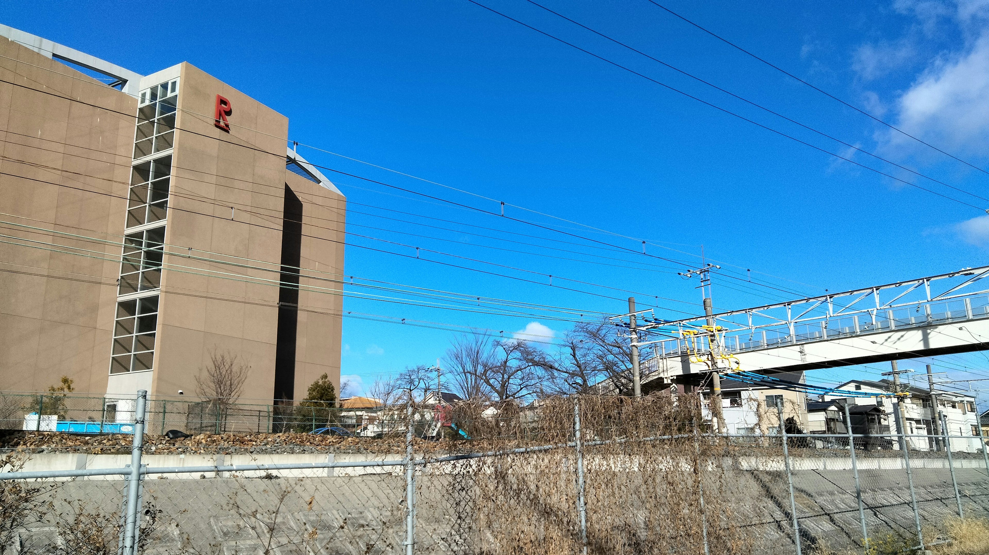 View of a tall building with a blue sky railway bridge and power lines visible