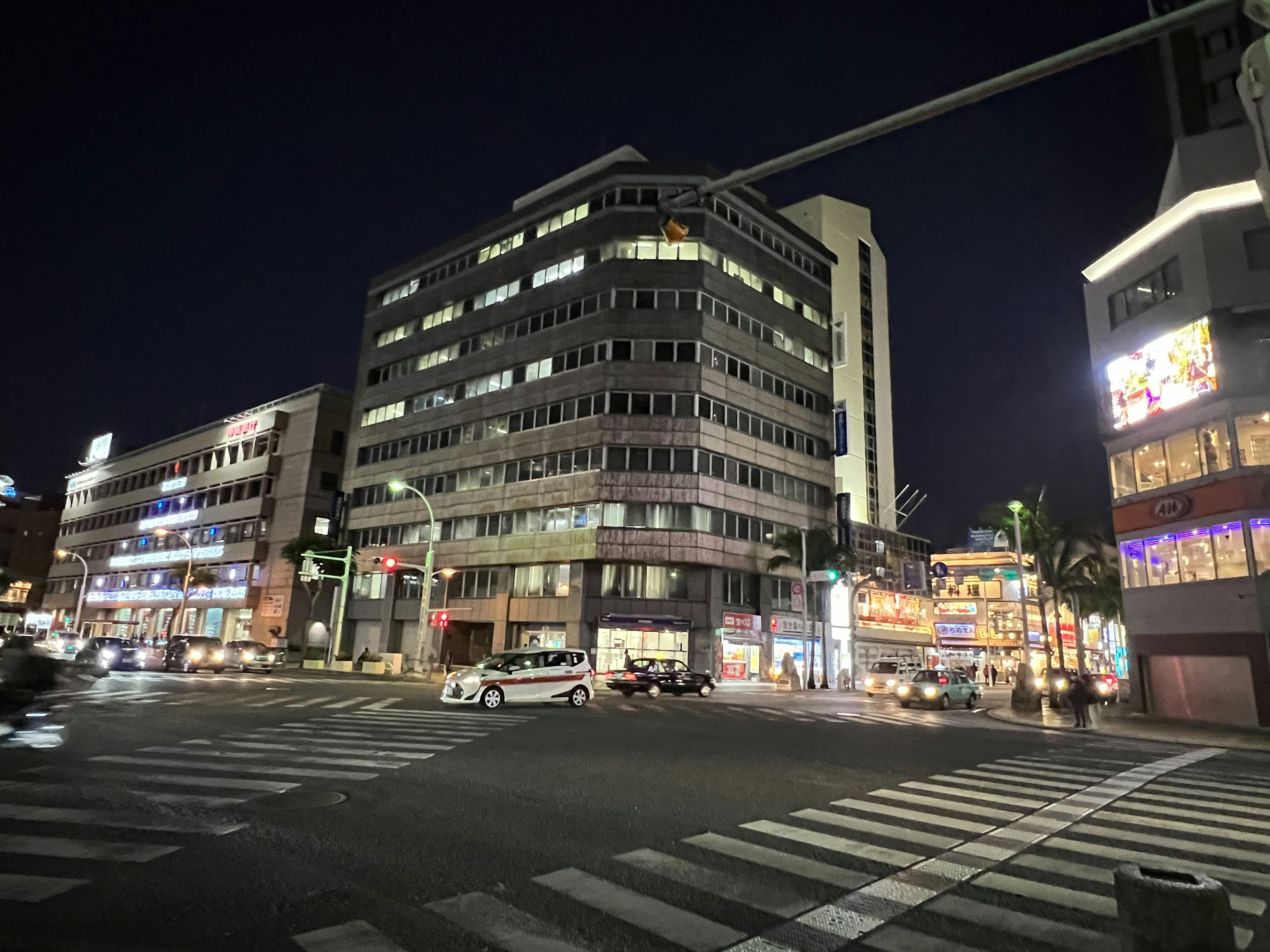 Scenario urbano notturno con un edificio moderno e insegne luminose a un incrocio