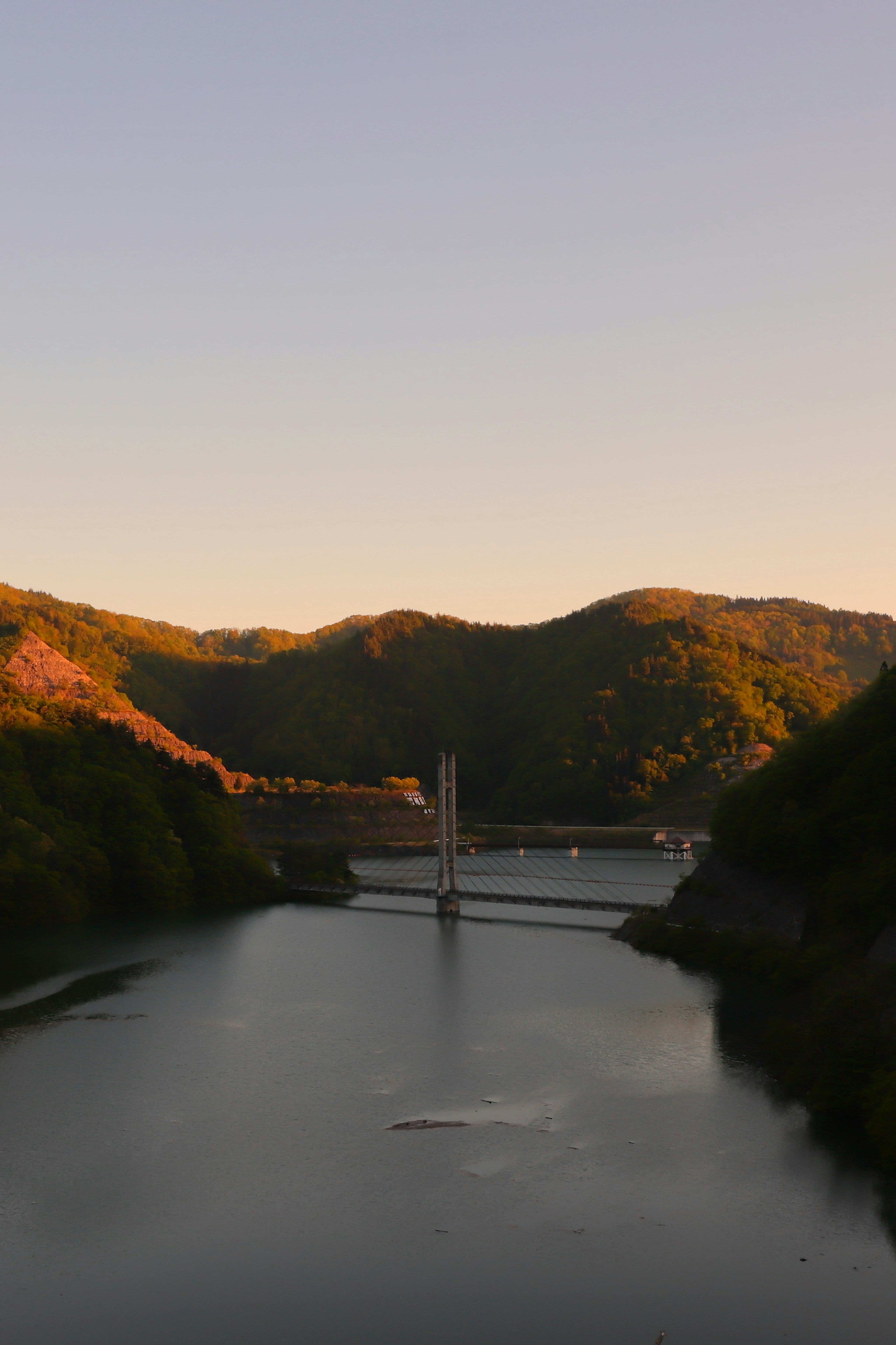 Vue sereine d'une rivière avec un pont entouré de montagnes