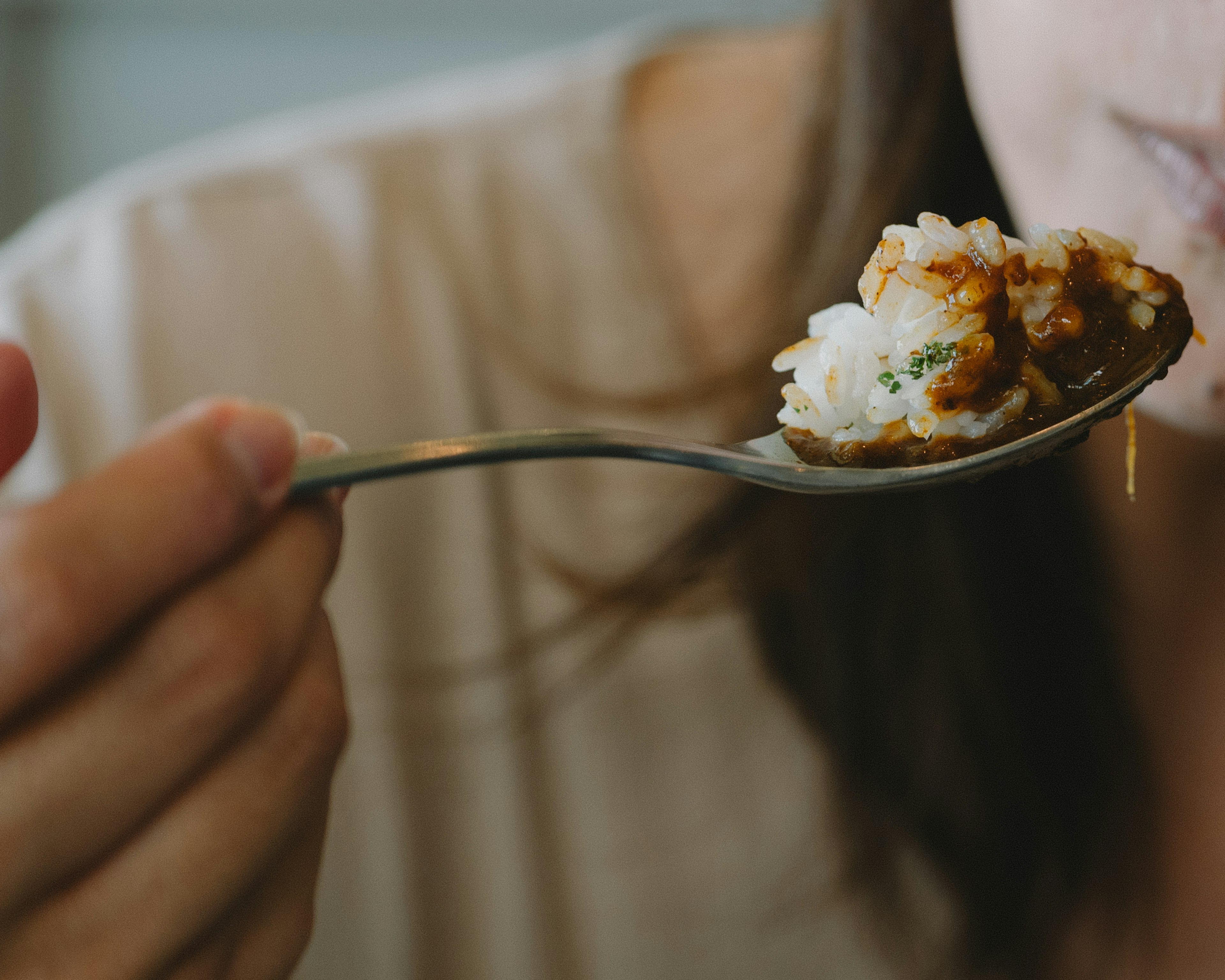 Close-up of a woman holding a spoonful of rice