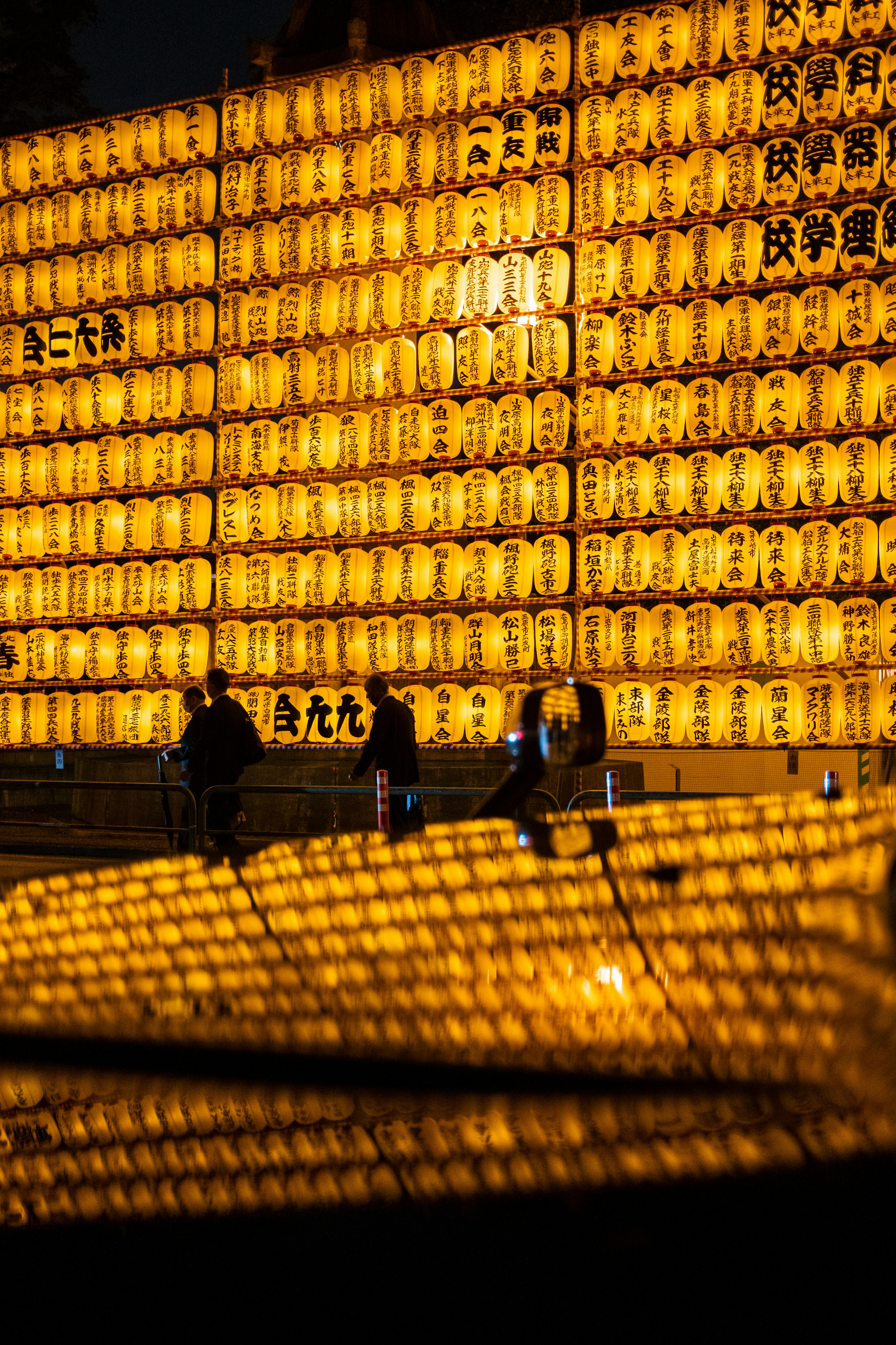 Silhouettes of people against a backdrop of numerous illuminated lanterns at a night festival