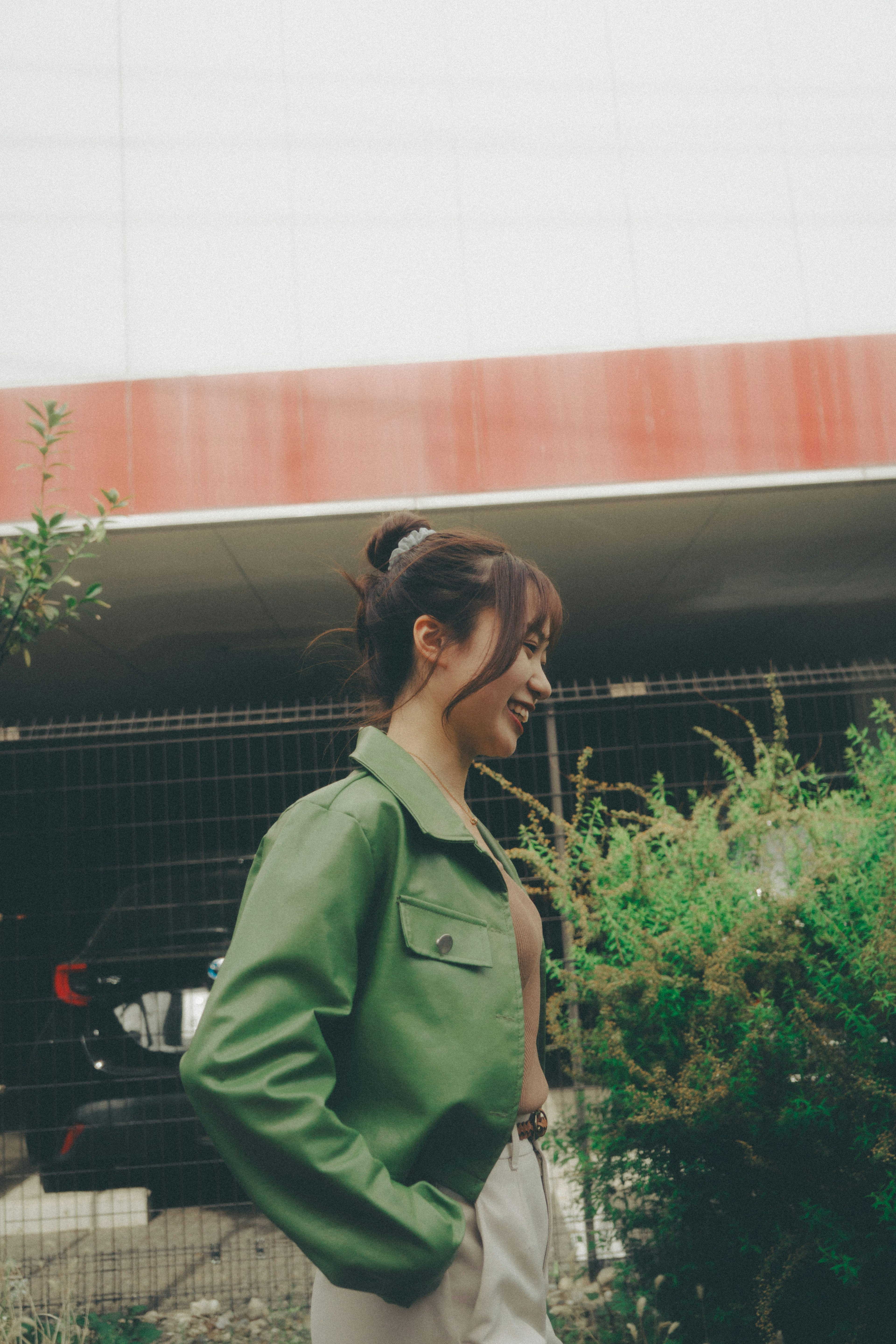 Femme en veste verte marchant près des plantes