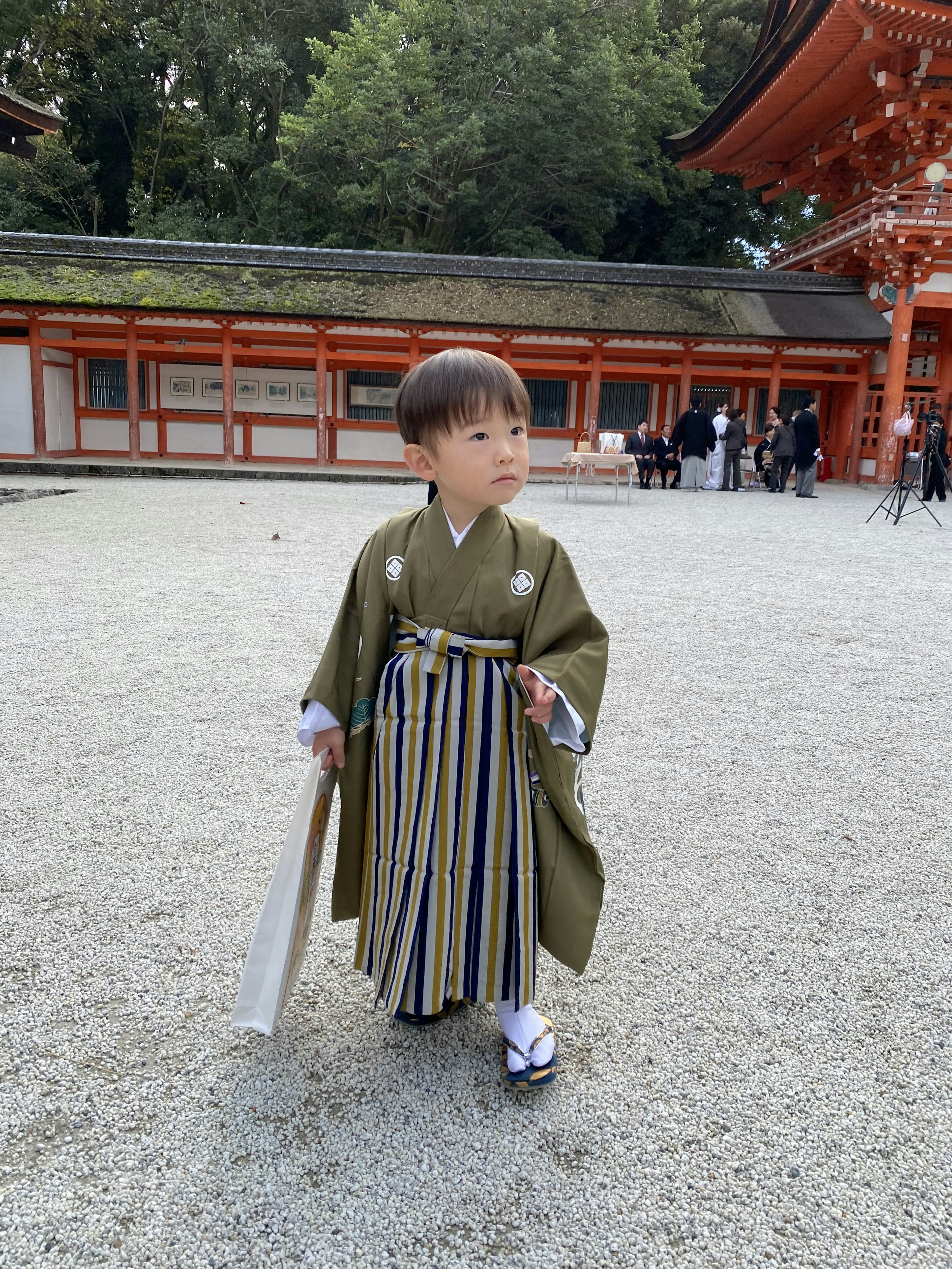 緑の着物を着た子供が神社の前で立っている