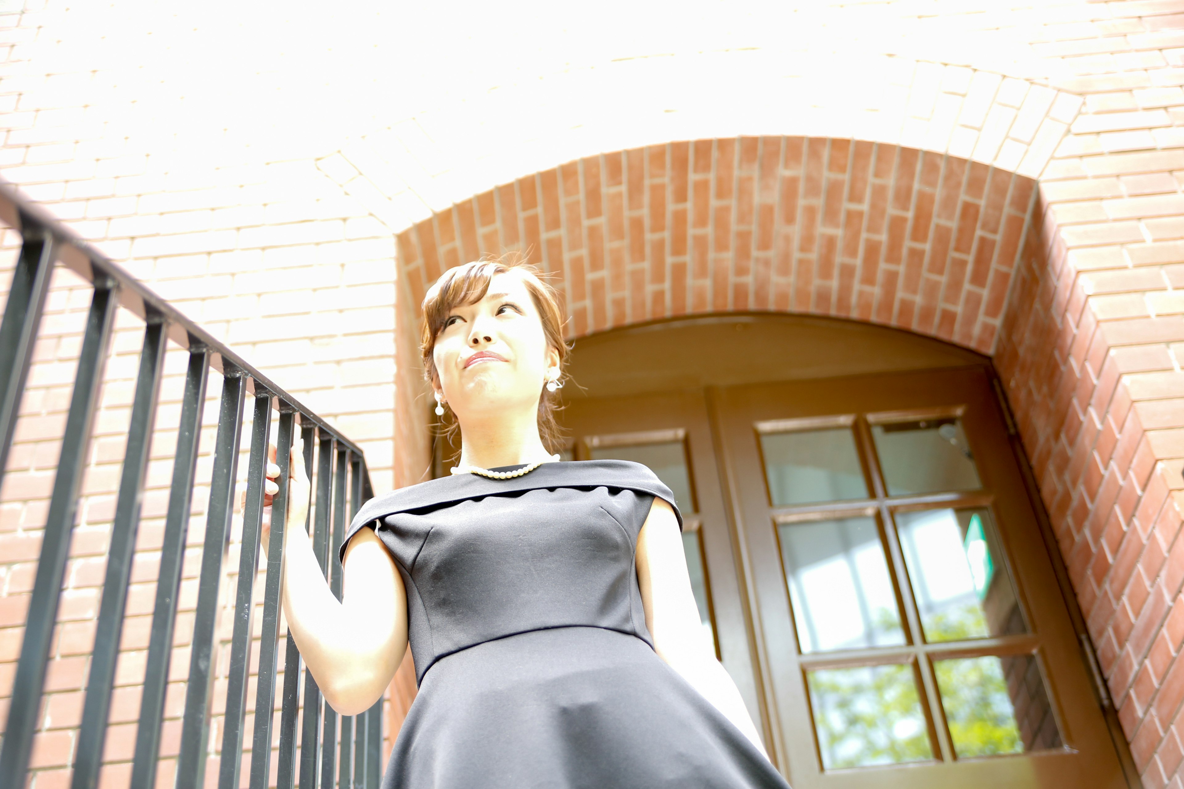 Woman ascending stairs with bright background and brick arch