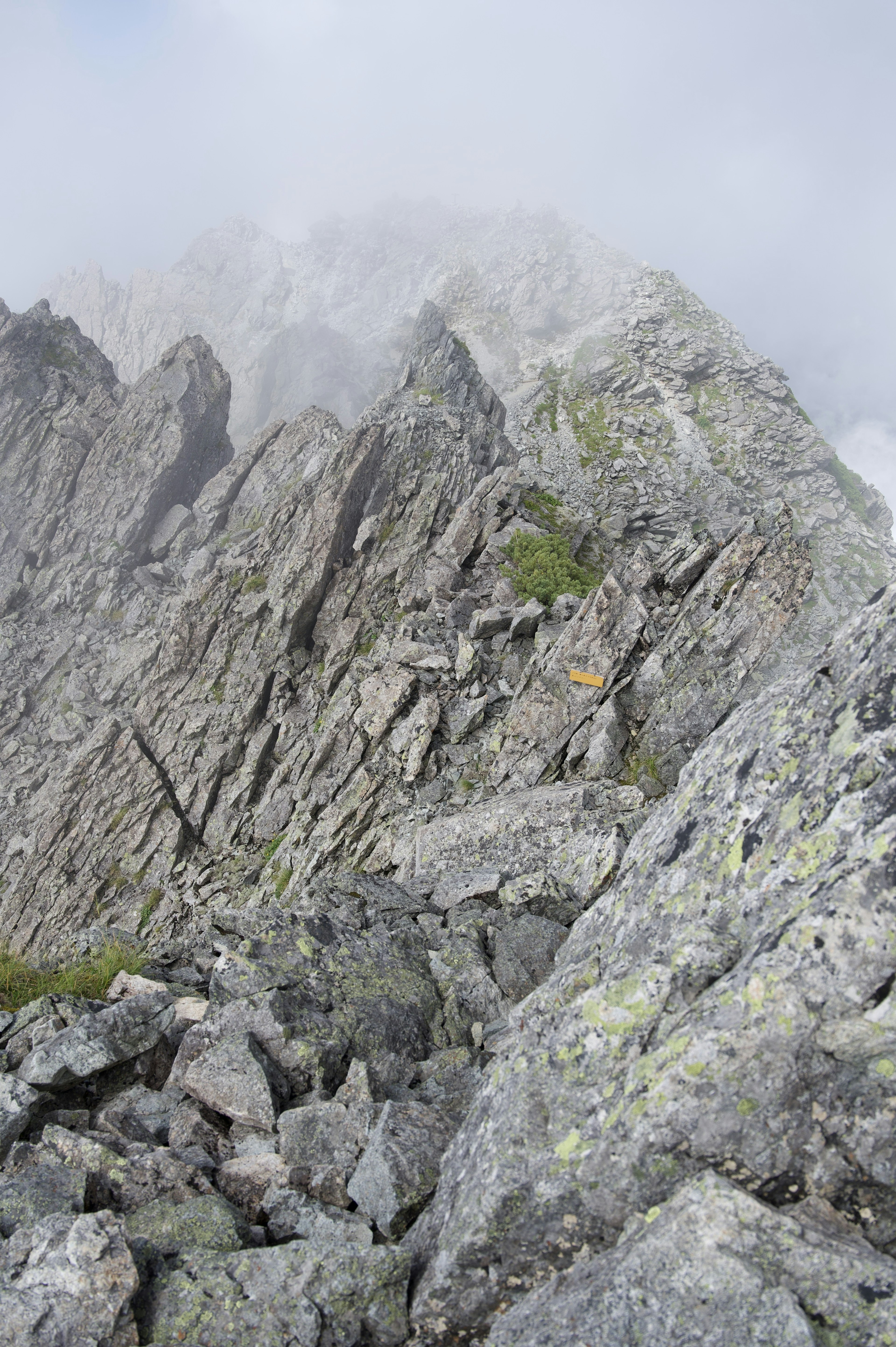 Cimes montagneuses rocheuses enveloppées de brume avec un terrain escarpé