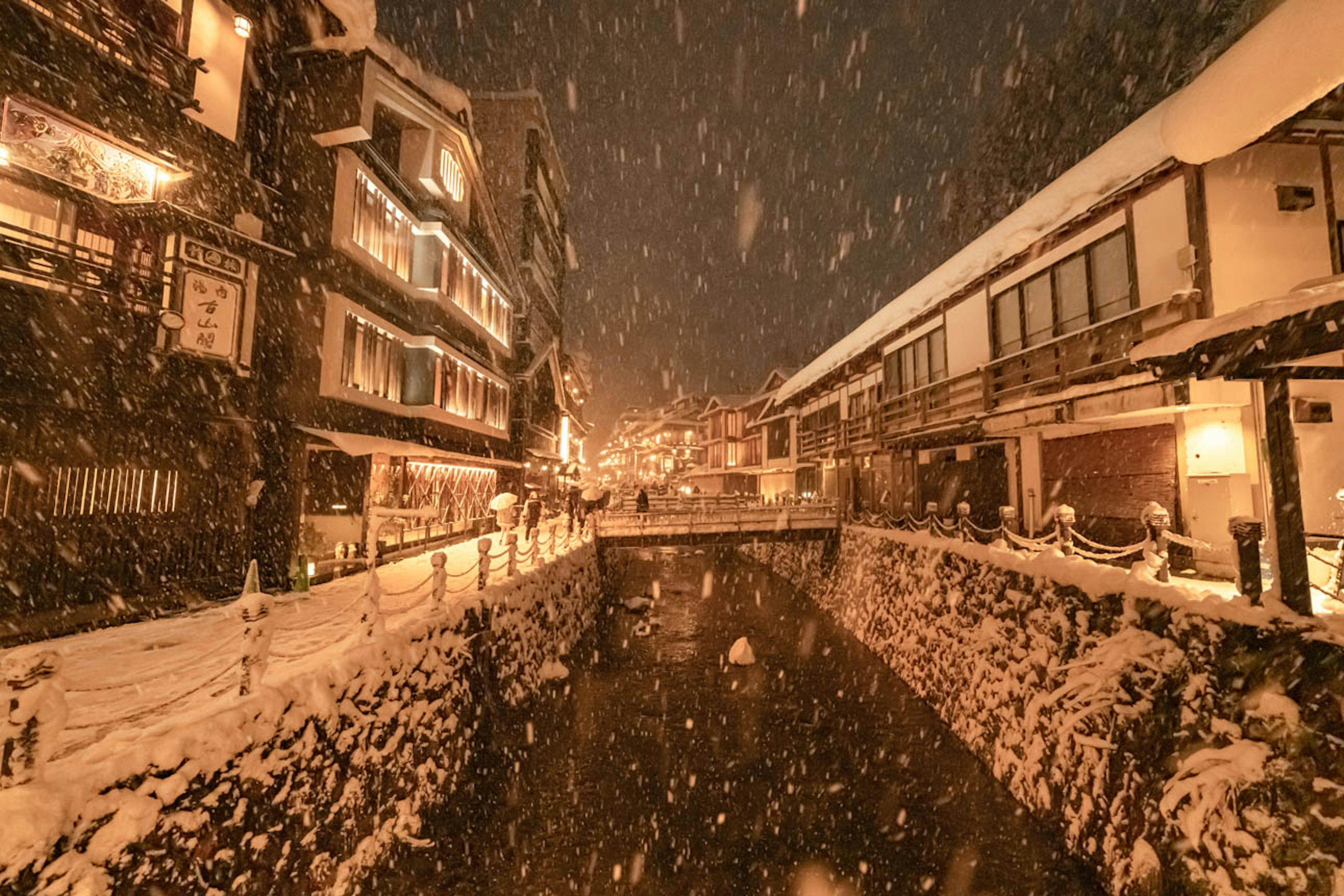 Escena nocturna nevada de una ciudad termal con un río