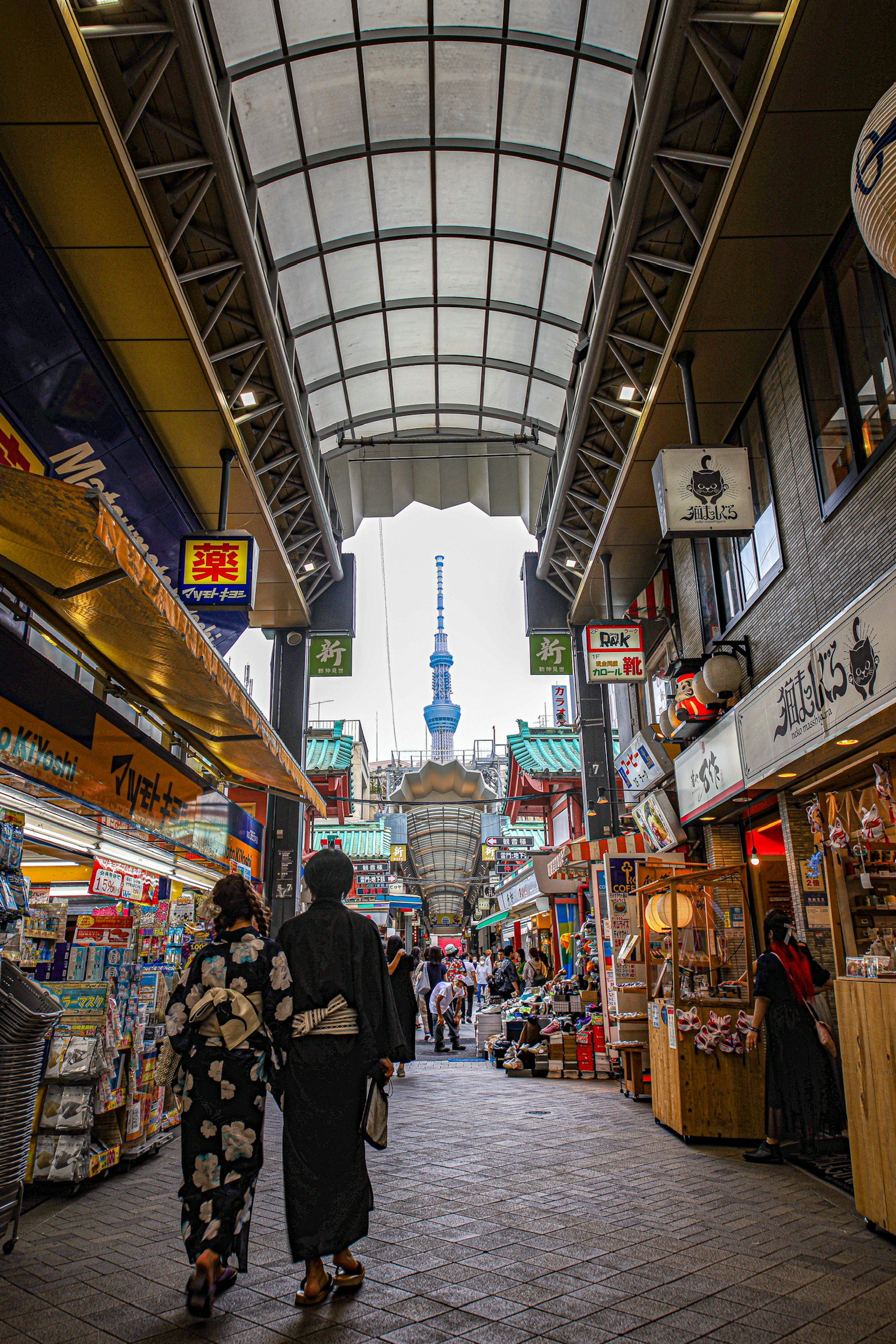 Des personnes en kimono marchant dans une arcade commerçante avec la Tokyo Skytree en arrière-plan