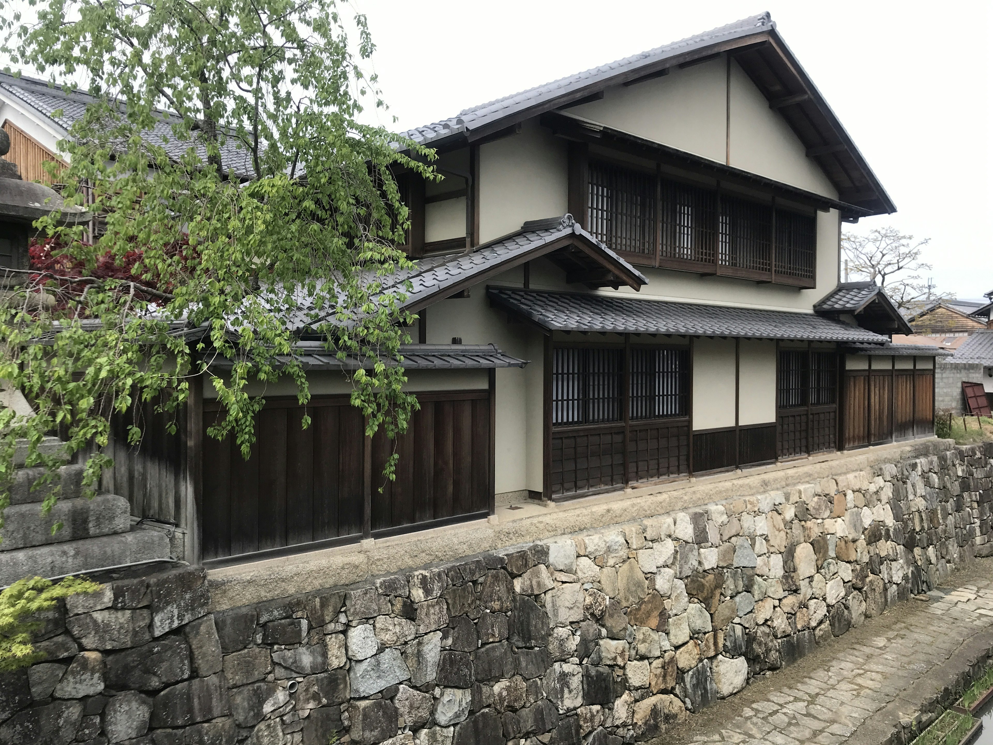 Eksterior rumah Jepang tradisional dikelilingi dinding batu