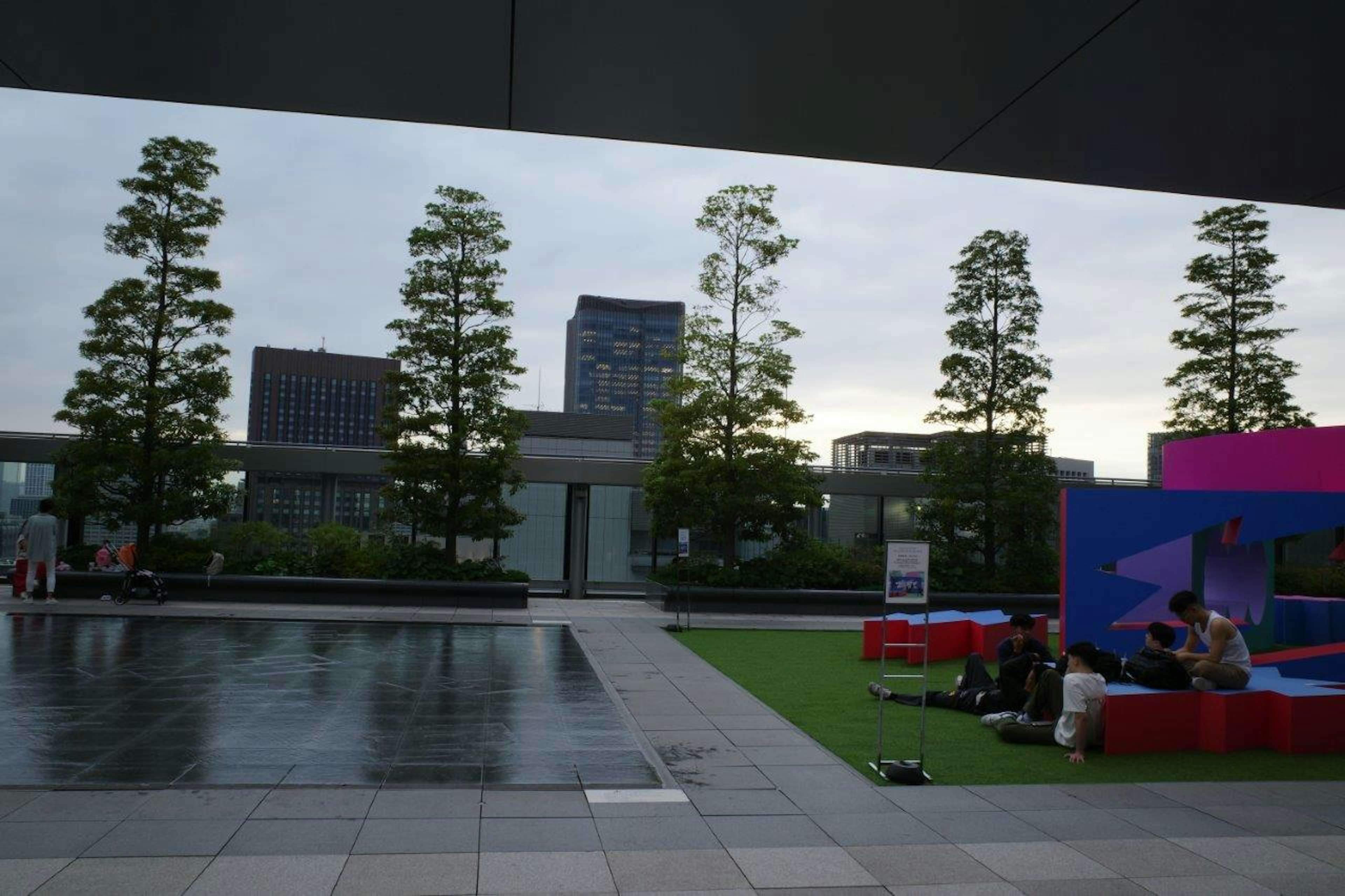 Outdoor space with modern buildings and green trees featuring people gathered