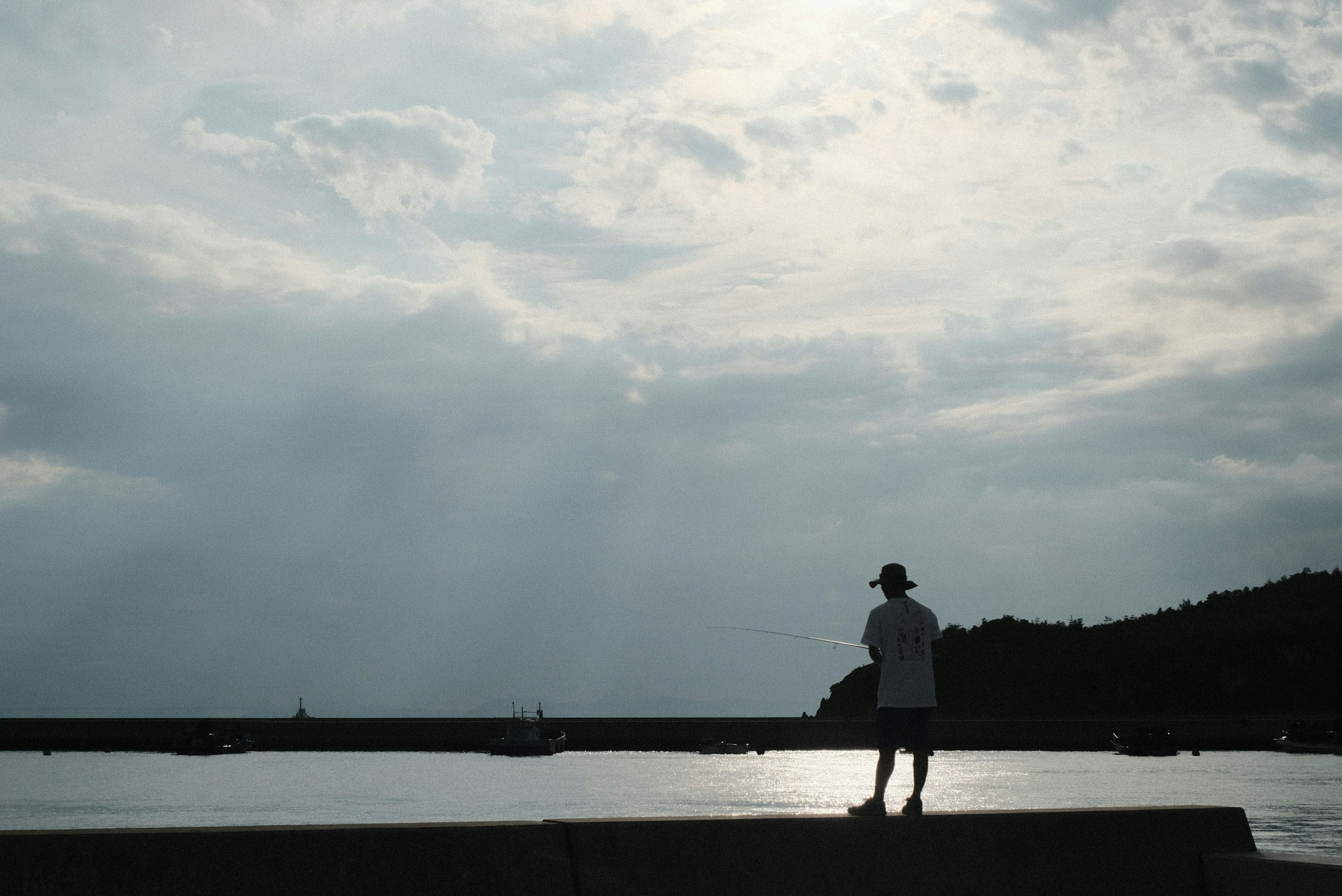 海辺で立つ人物と曇り空の風景