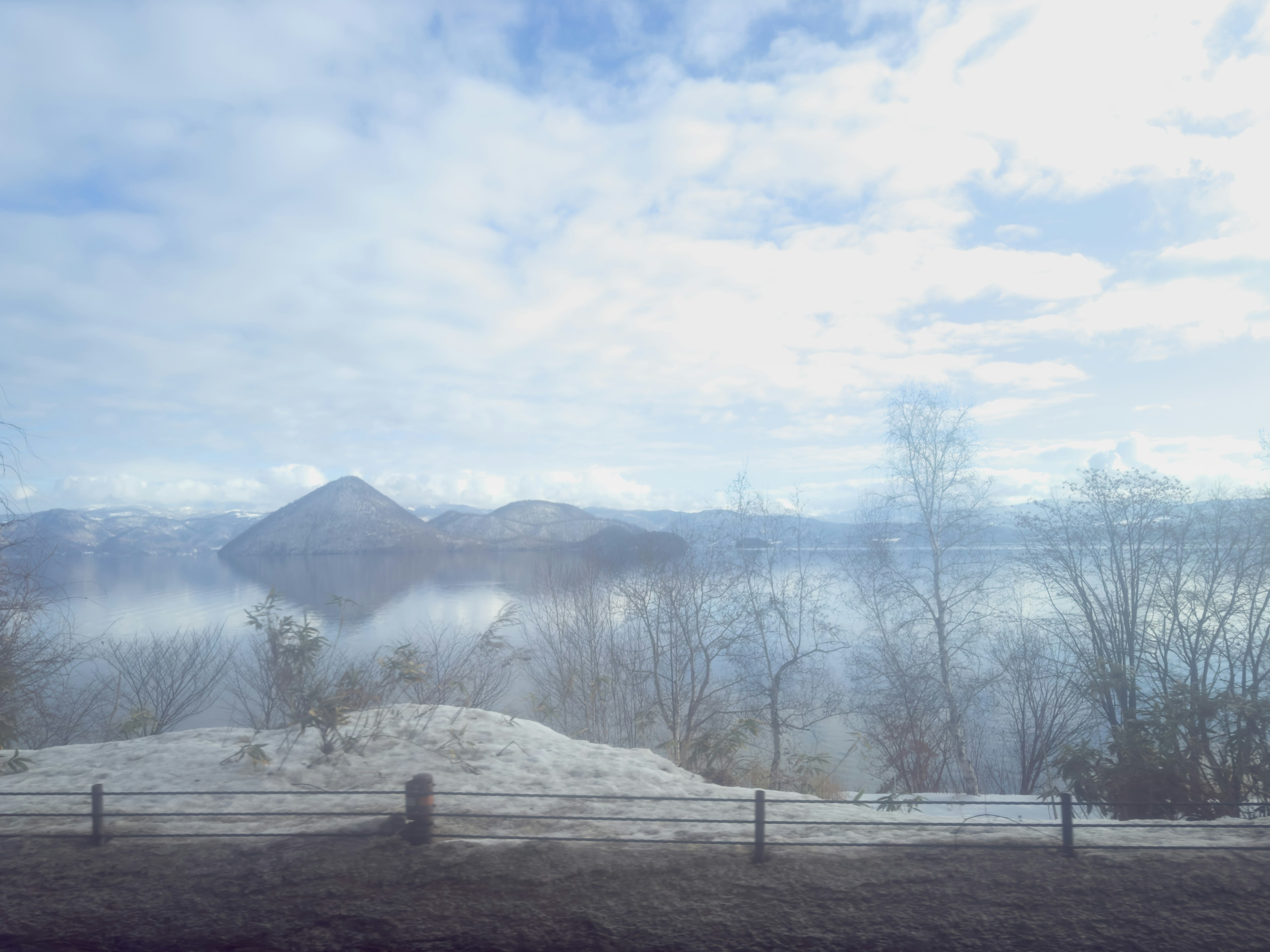 Wunderschöne Landschaft mit in Nebel gehüllten Bergen und schneebedecktem Boden