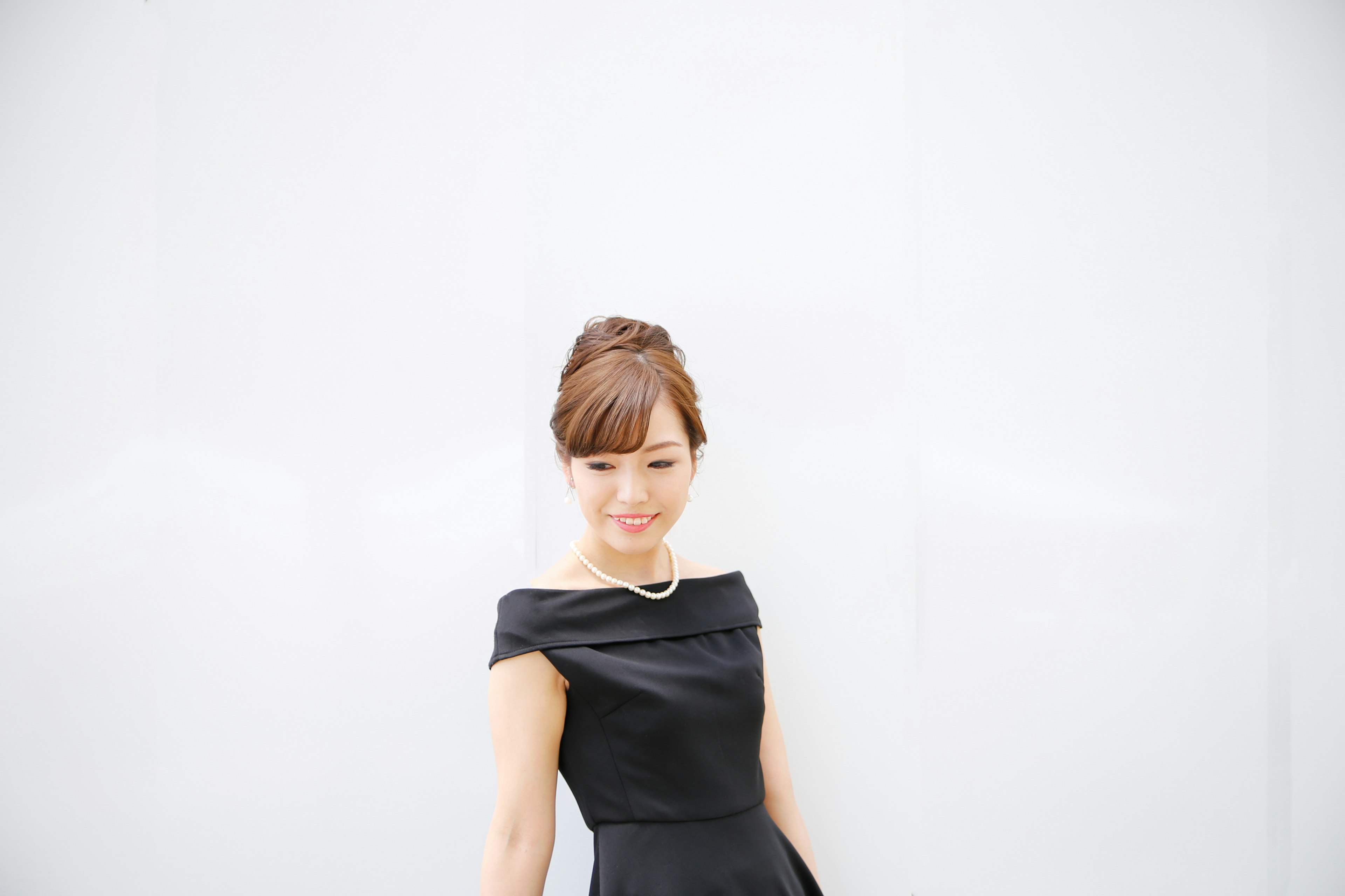 A woman in a black dress standing against a white background