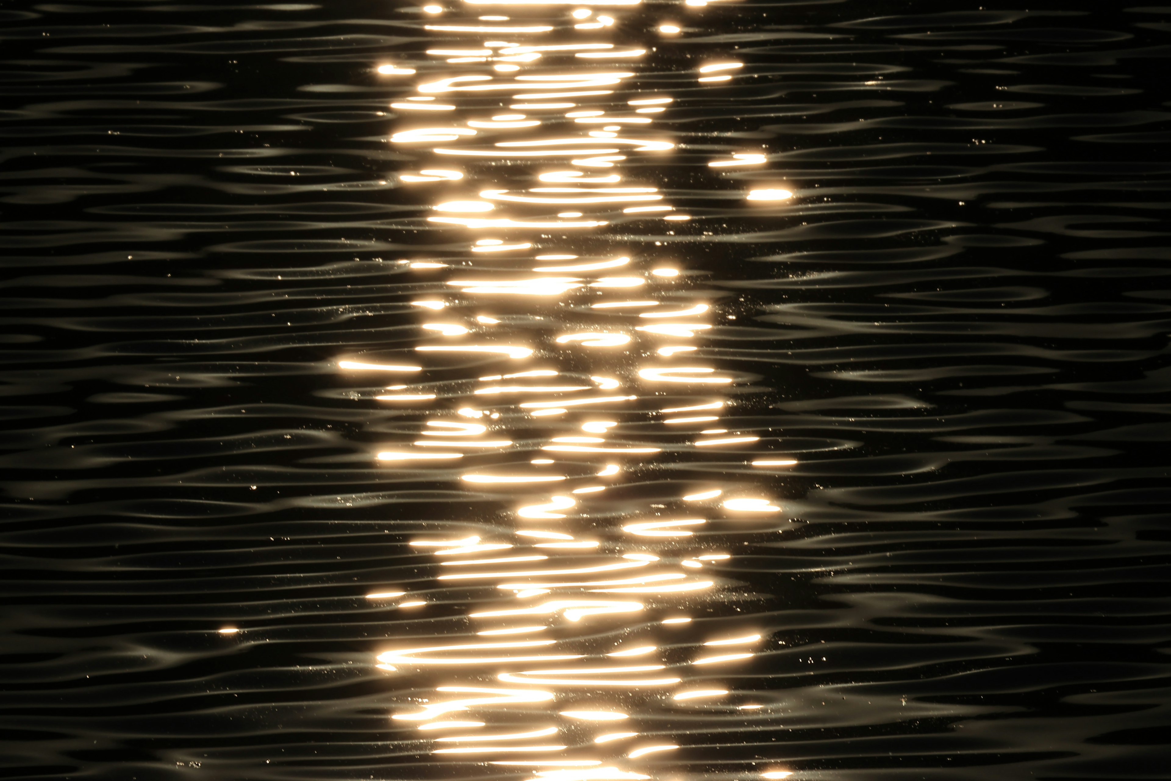 Image of light patterns reflecting on water surface with a dark background