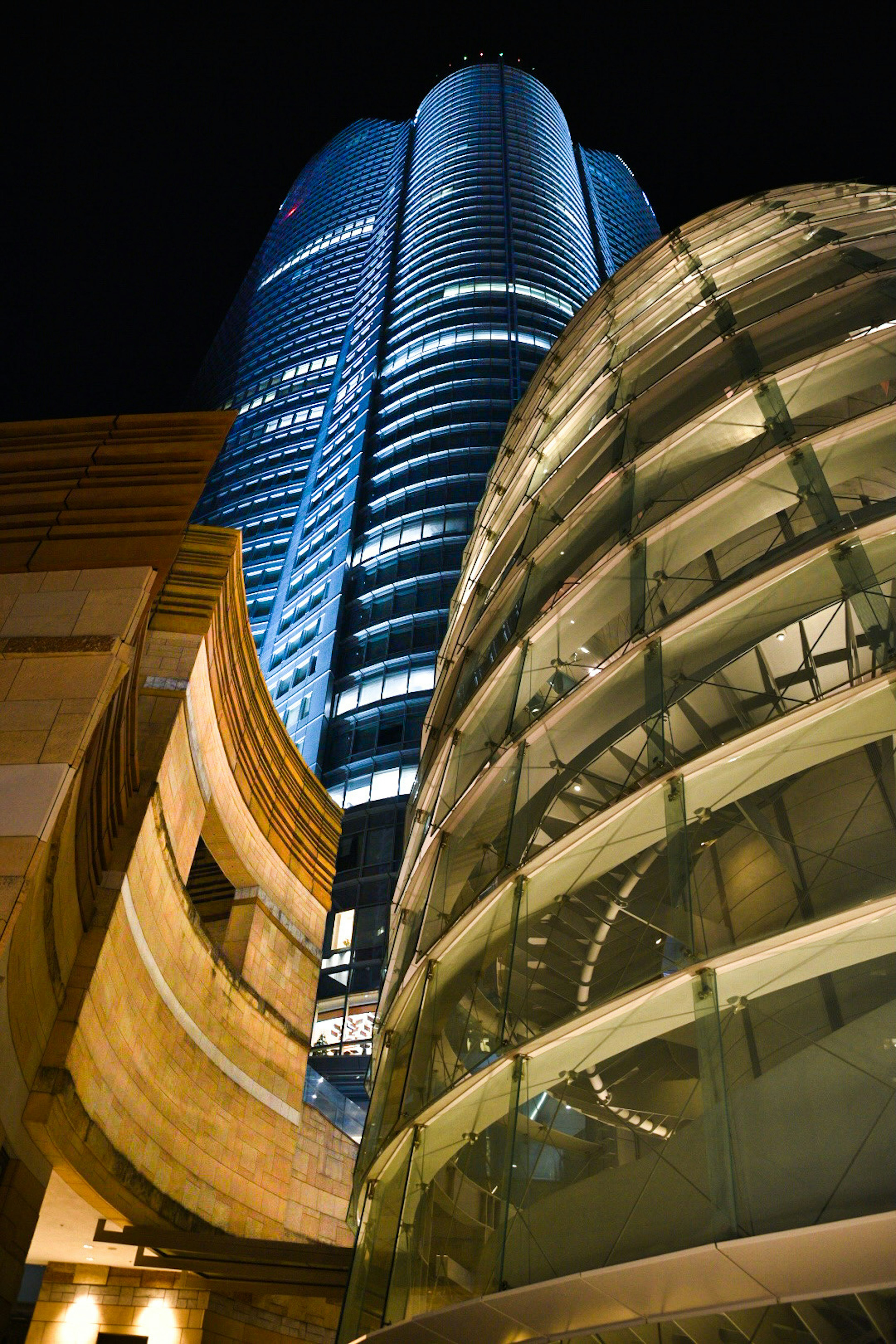 Vista nocturna de un rascacielos y una estructura de vidrio