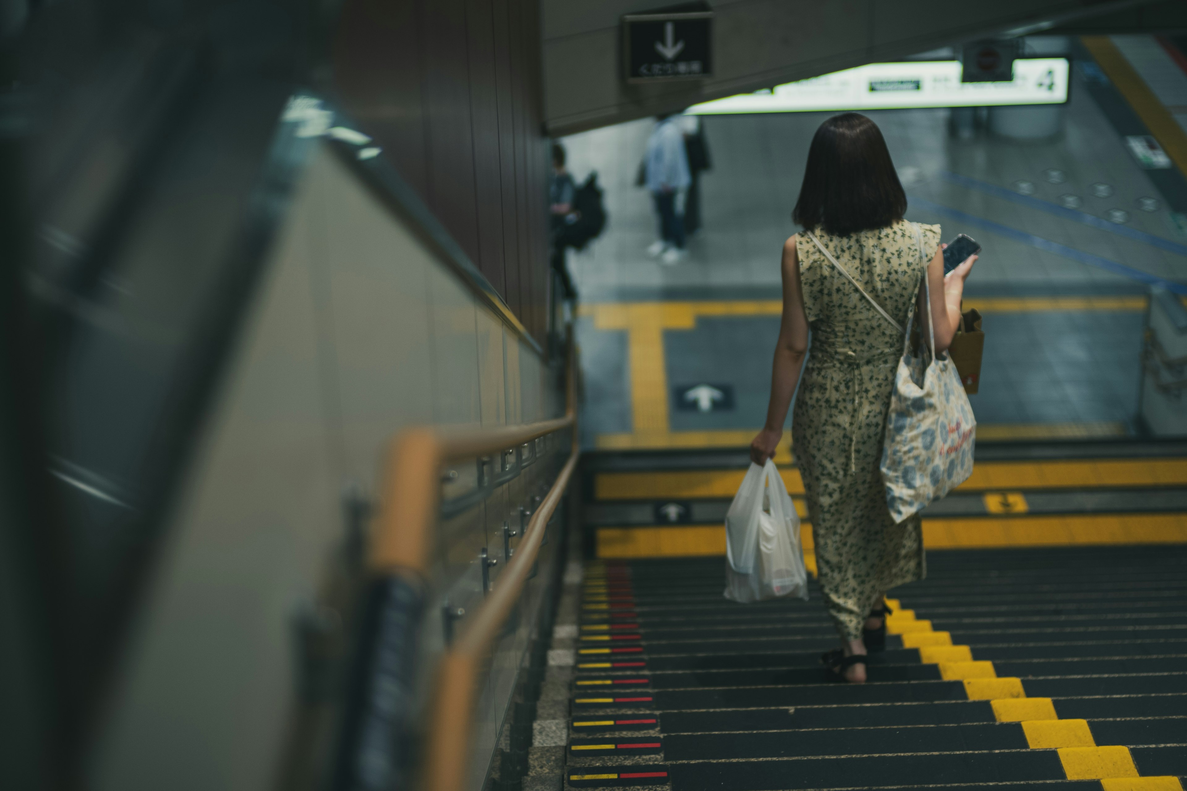 女性走下楼梯，休闲服装，手里提着袋子