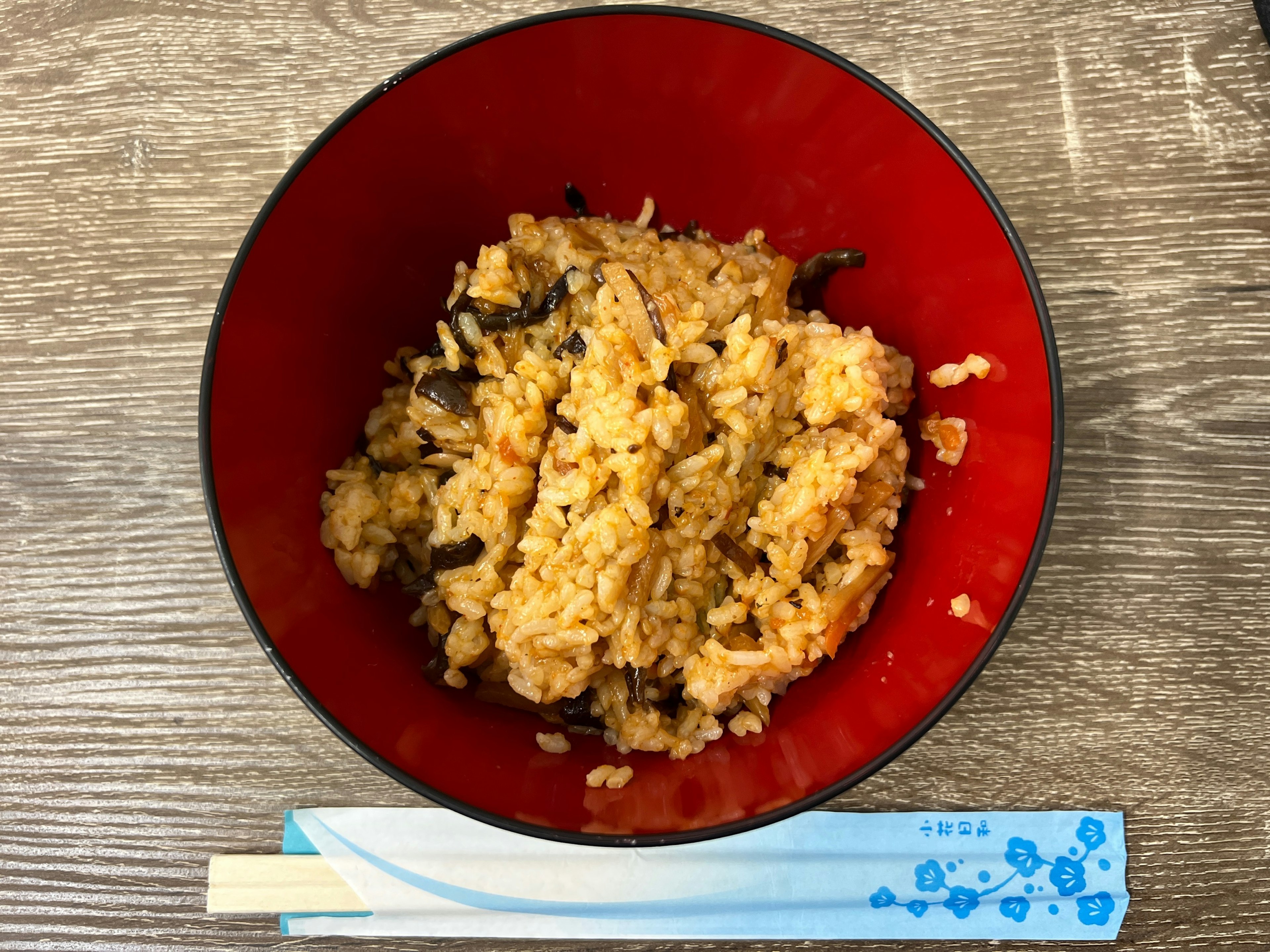 Image of seasoned rice in a red bowl on a wooden table