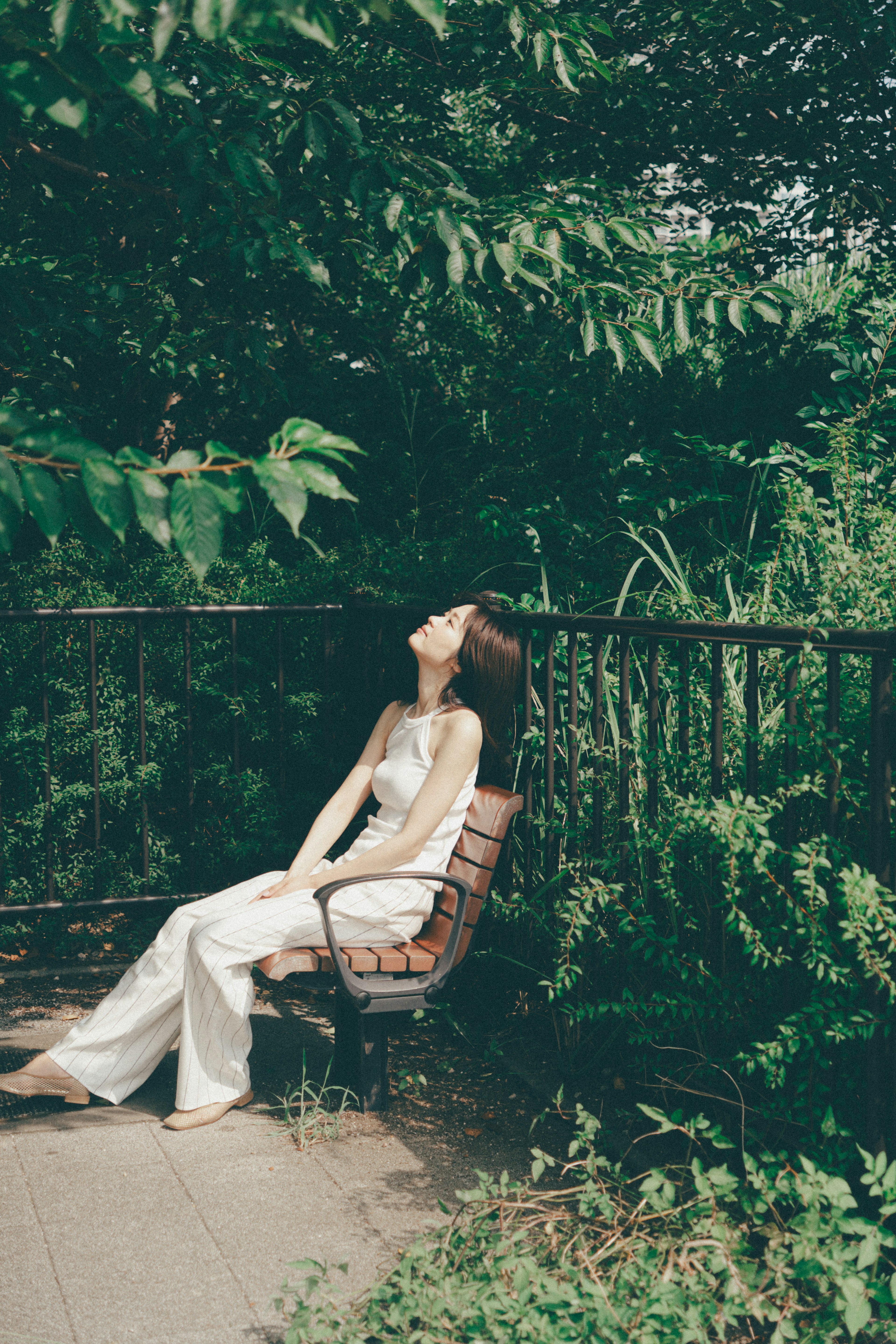 Woman relaxing in a lush green setting sitting on a bench