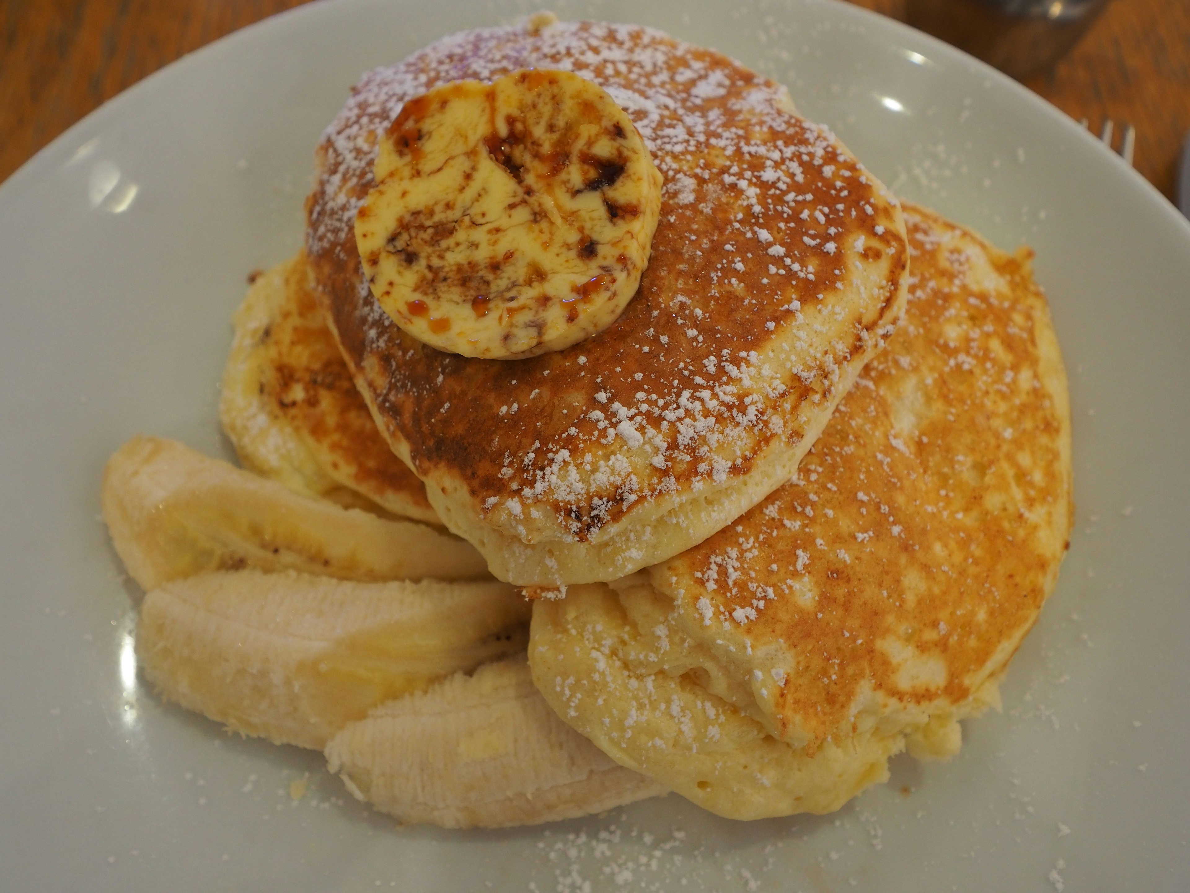 Pancakes esponjosos cubiertos con plátano y azúcar en polvo