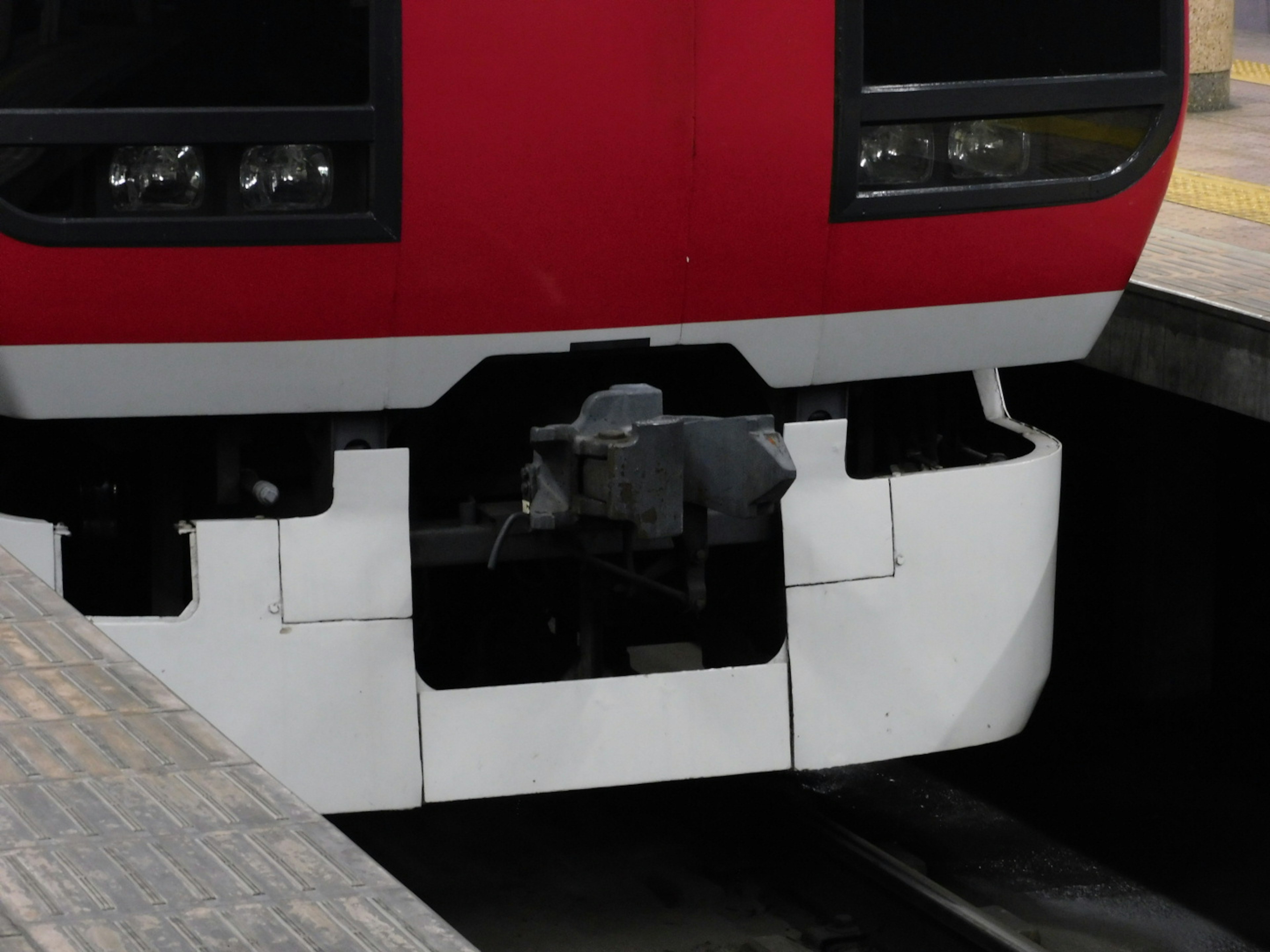 Close-up bagian depan kereta merah dan sambungan ke platform