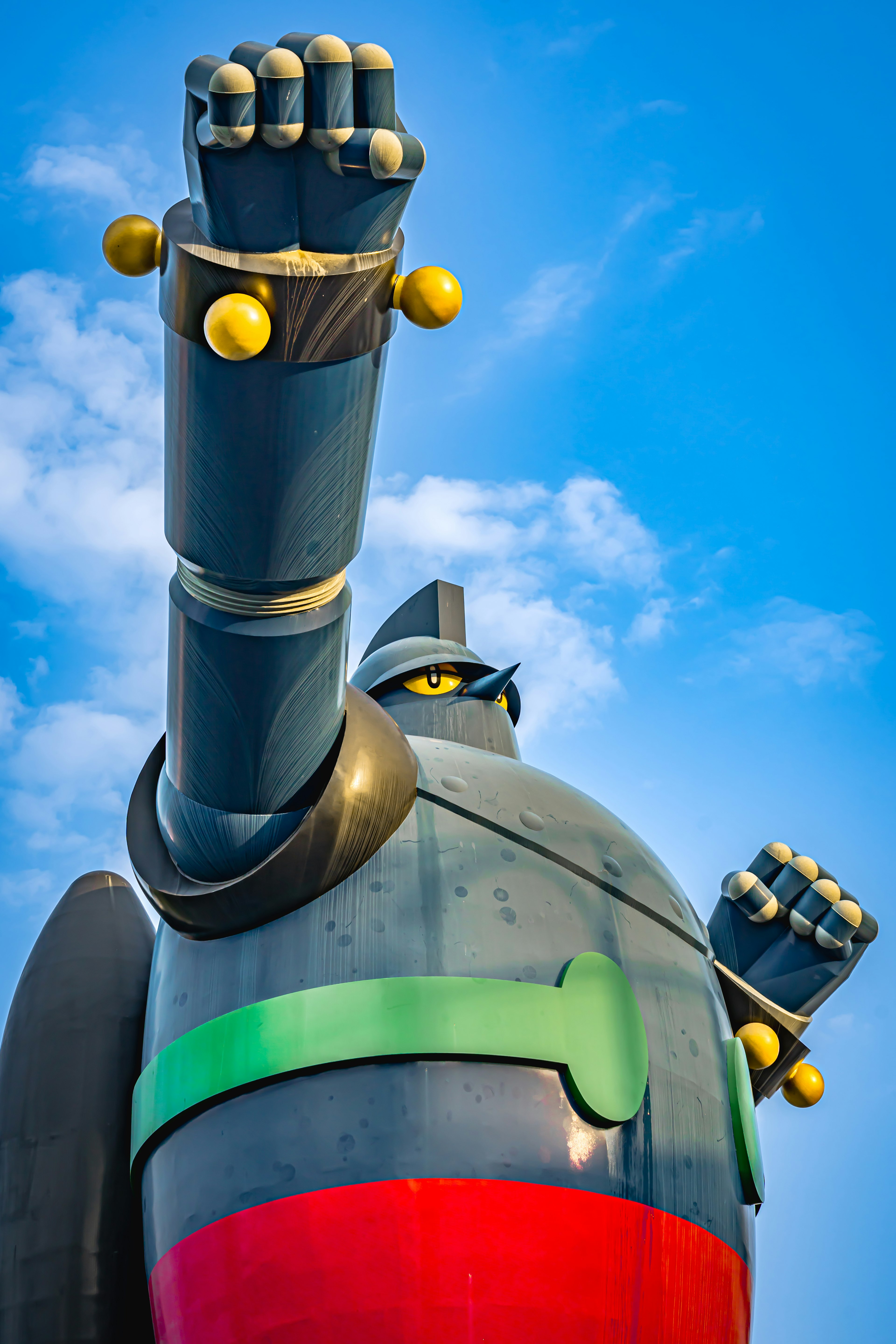 Large robot statue raising its arm under a blue sky