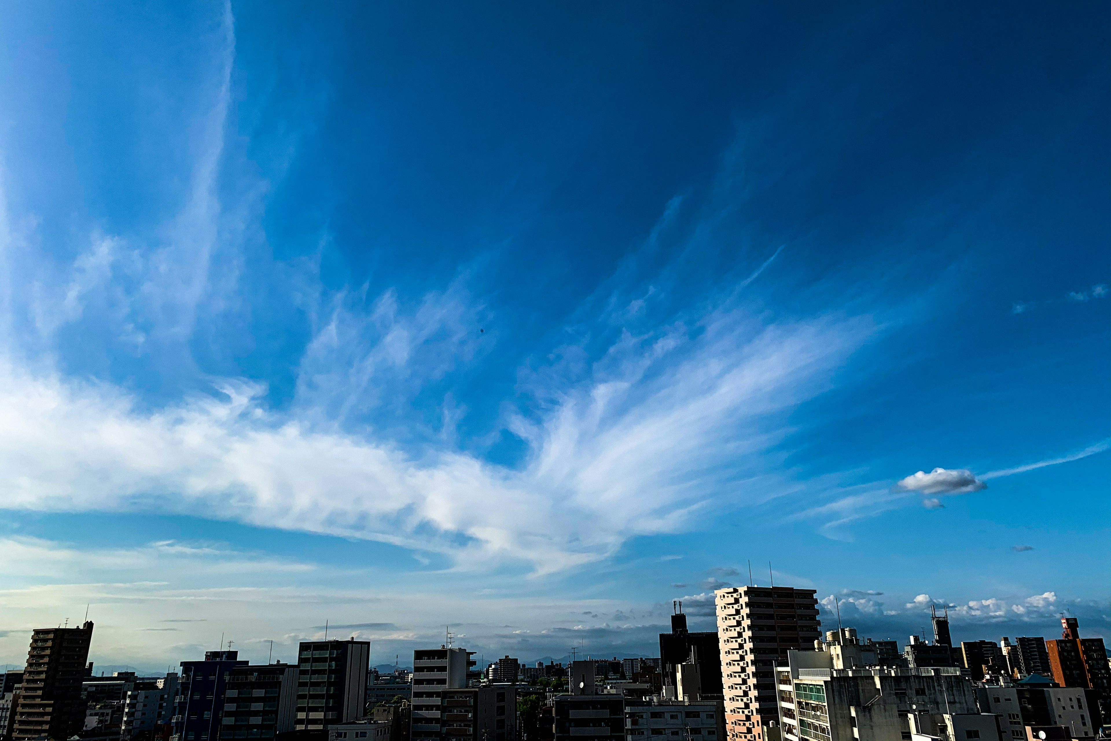 青空と白い雲が広がる都市の景色