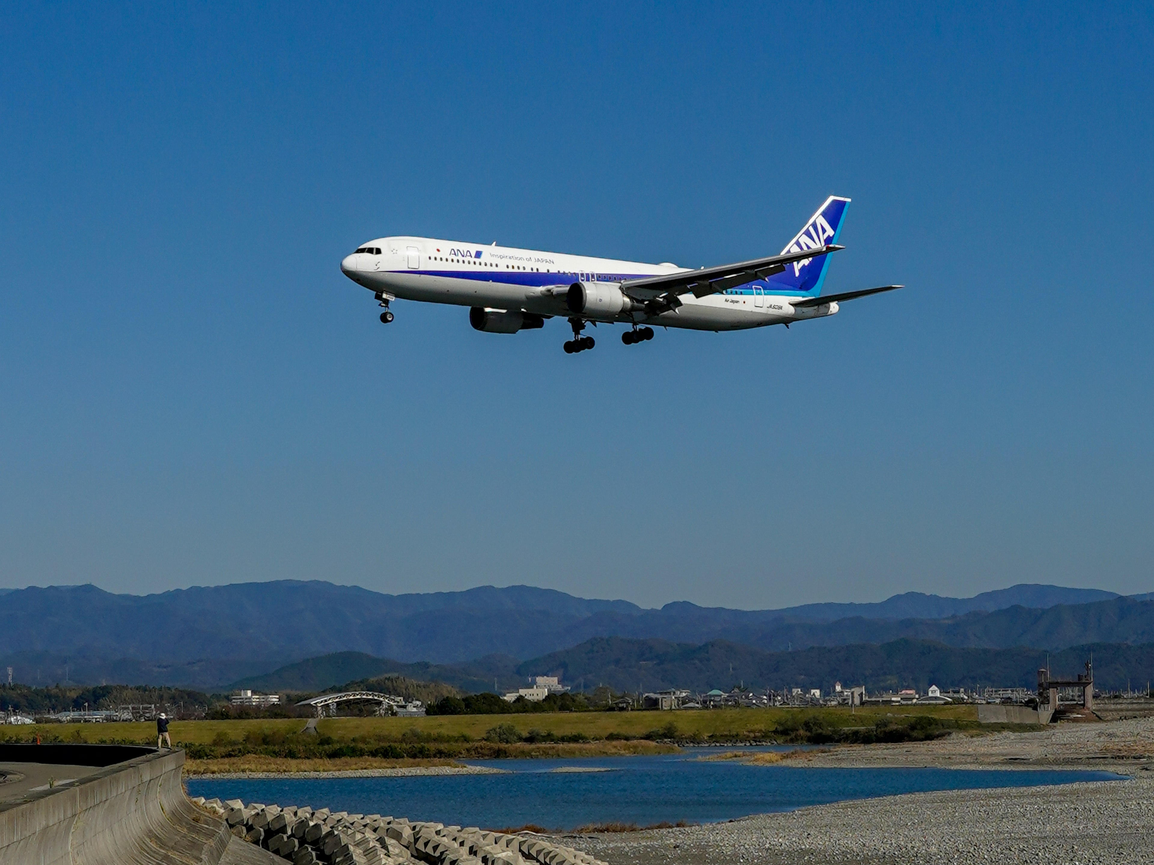 Avión en aterrizaje con cielo azul y paisaje de río