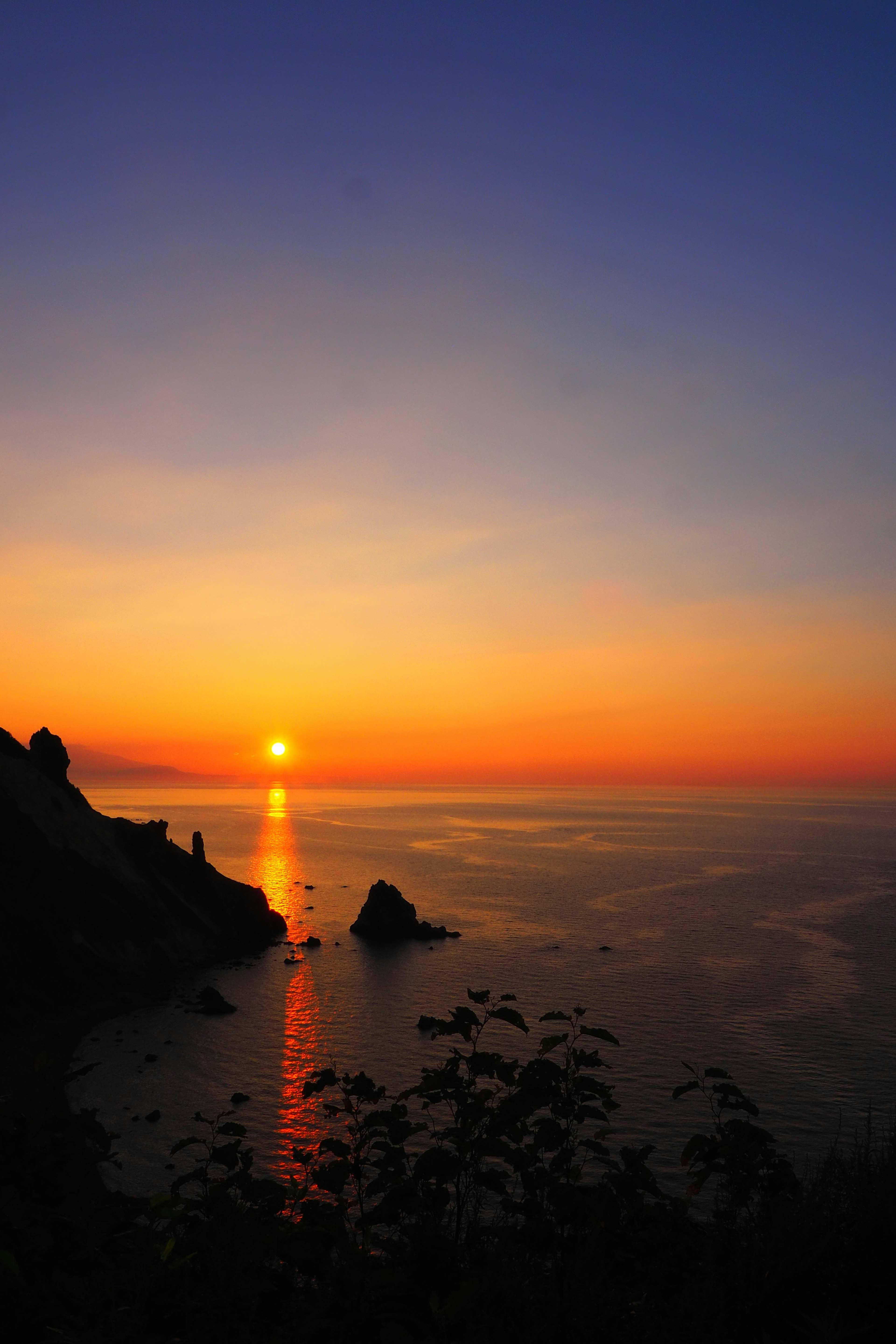 Magnifique coucher de soleil sur la mer avec le soleil se couchant à l'horizon et un ciel bleu