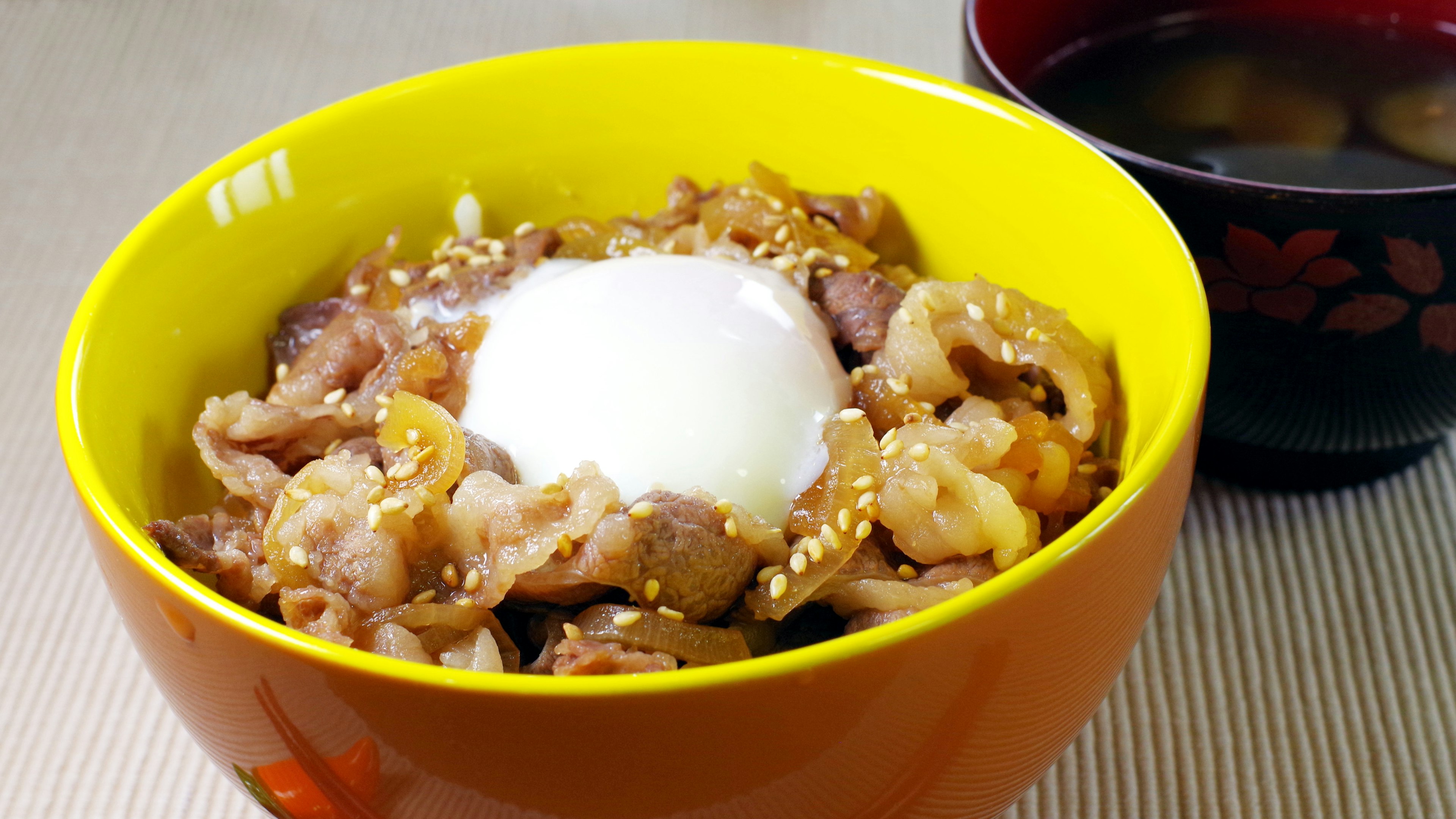 A vibrant bowl filled with rice and meat dish topped with a soft-boiled egg