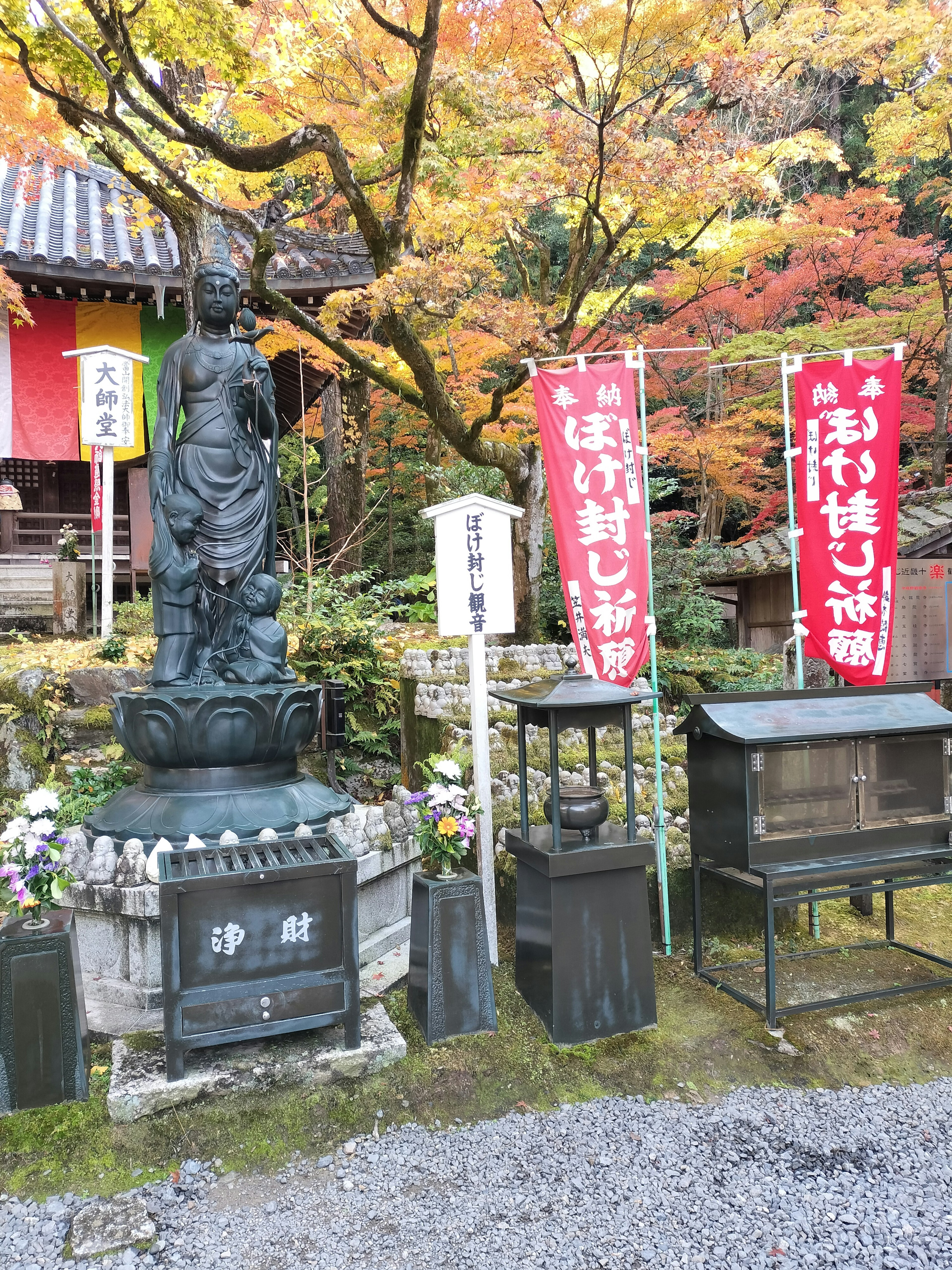 秋の紅葉に囲まれた仏像と赤い垂れ幕のある風景