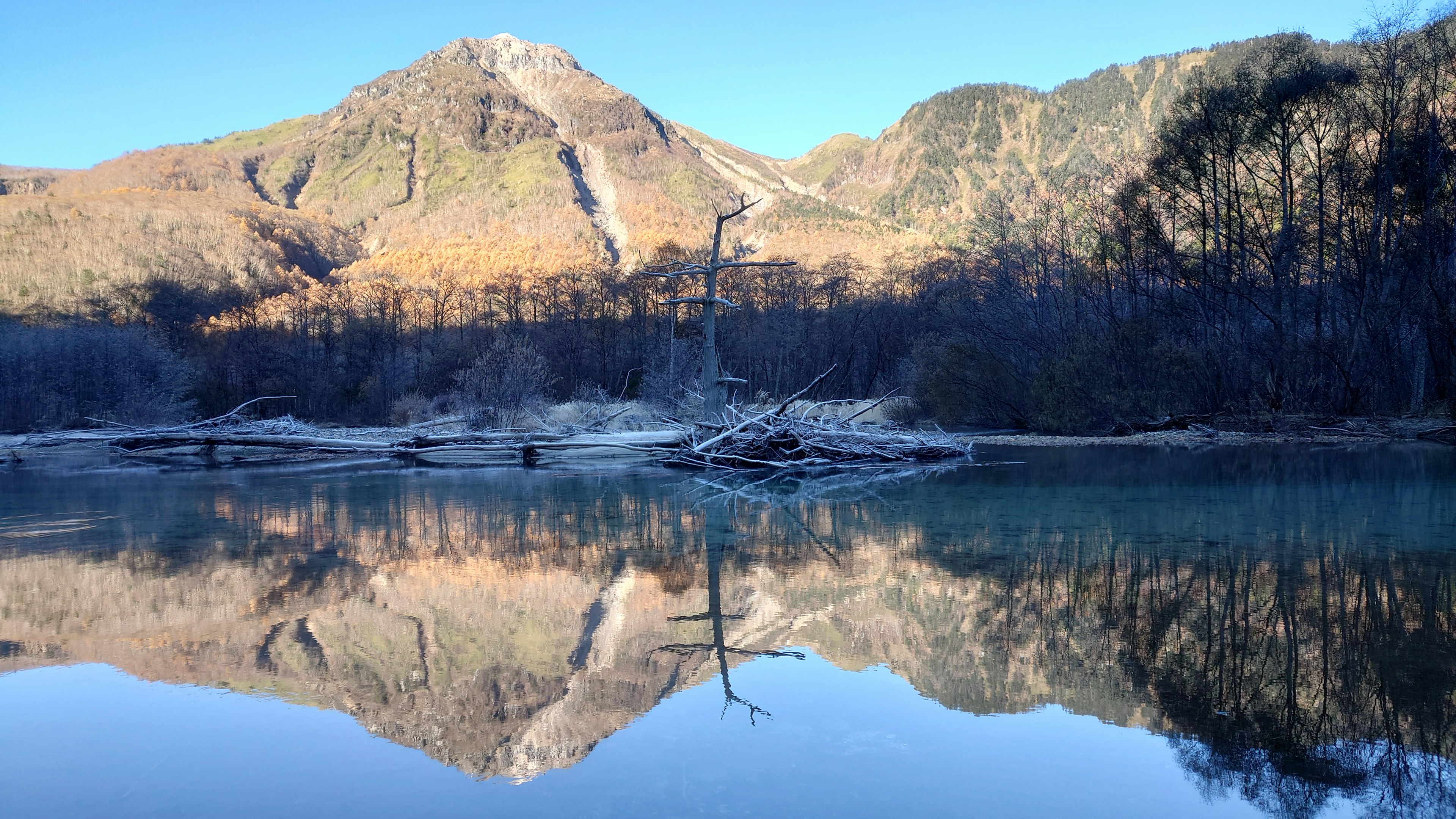 Vista panoramica di montagne e alberi morti riflessi su un lago calmo