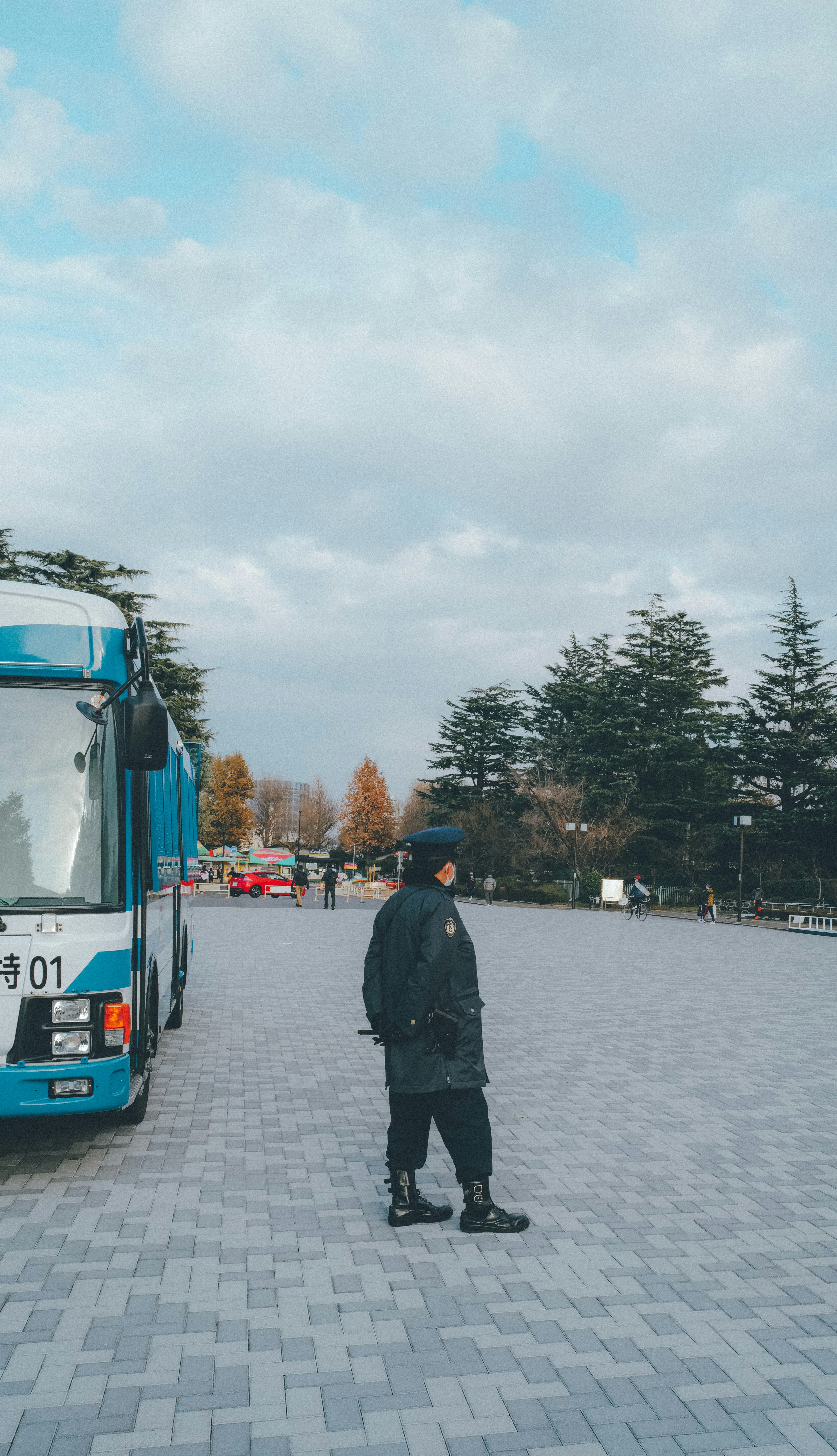 Security guard standing next to a blue truck with a cloudy sky