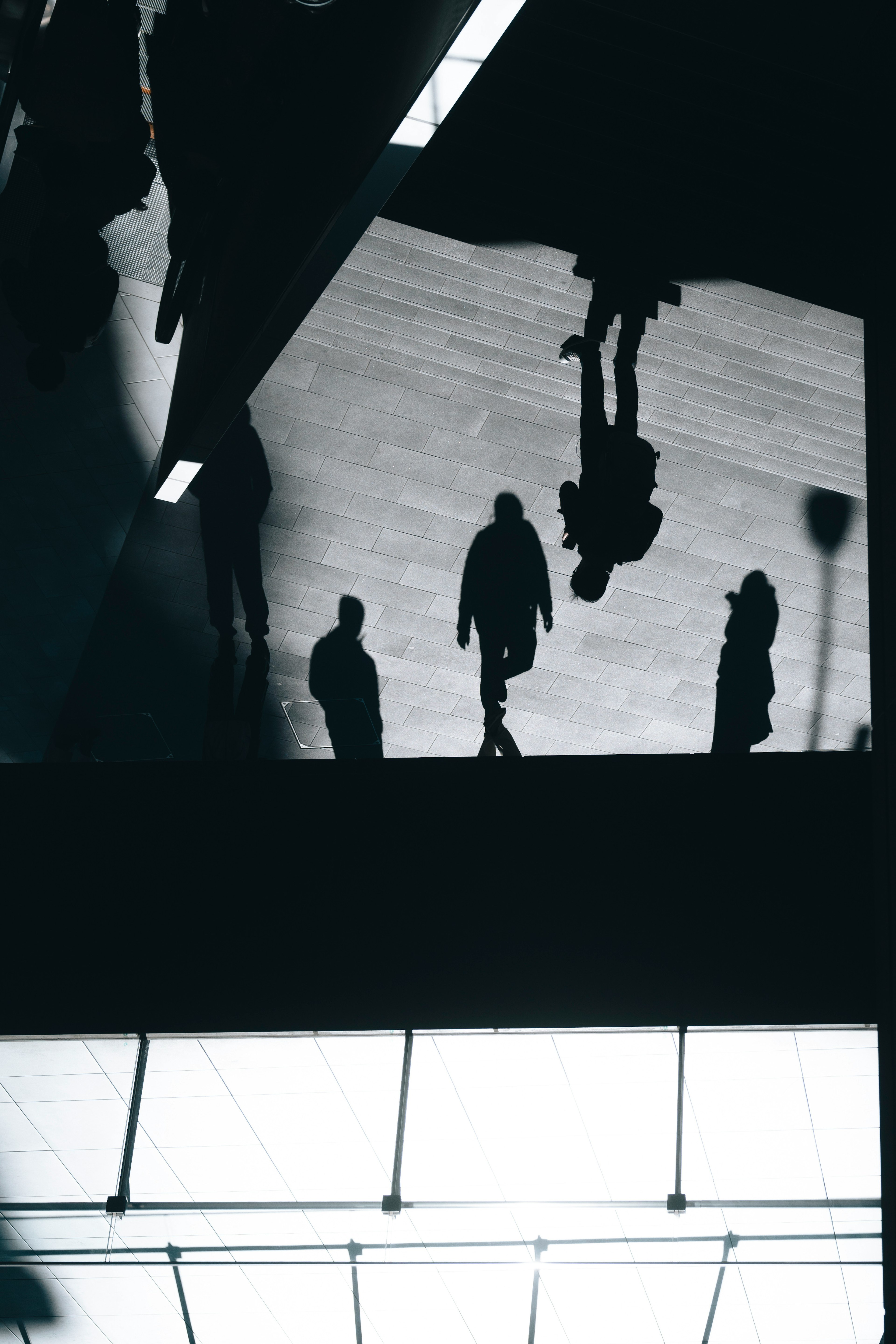 Schwarzweißbild von Personen, die mit Schatten gehen