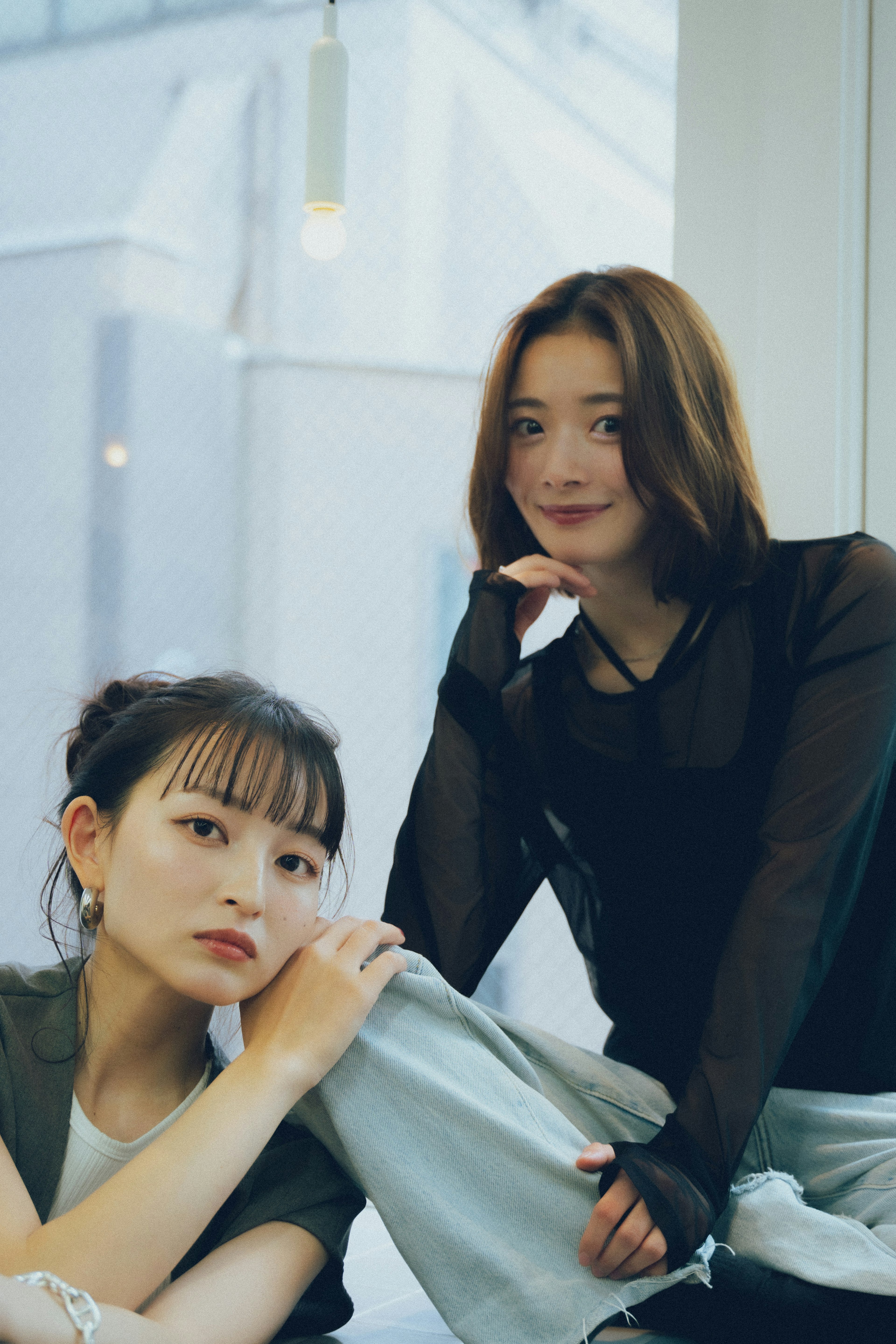 Dos mujeres posando cerca de una ventana con luz natural mostrando estilo de moda