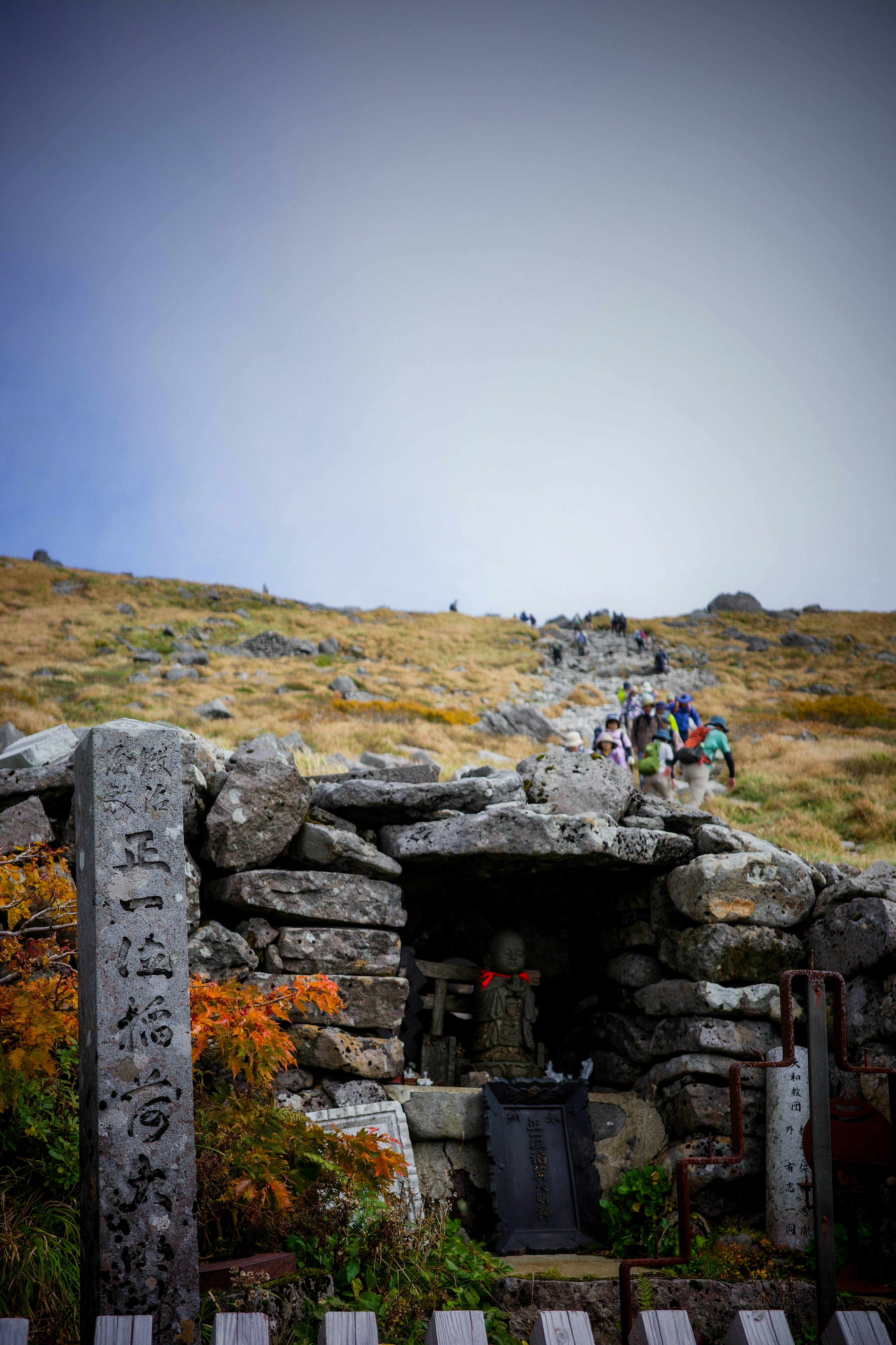 Vue panoramique d'une ancienne structure en pierre sur le flanc d'une montagne avec des randonneurs