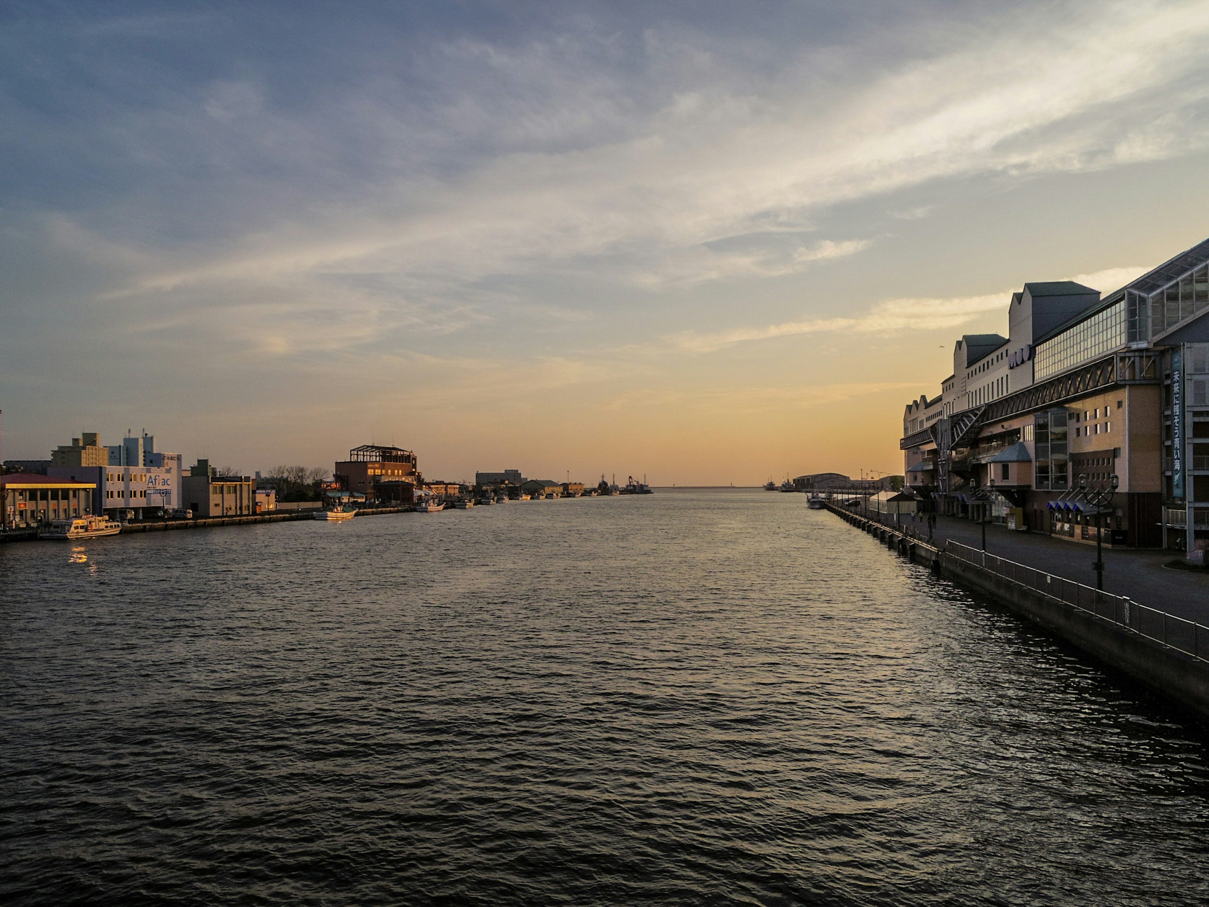 Vue pittoresque d'une rivière avec des bâtiments urbains et un coucher de soleil