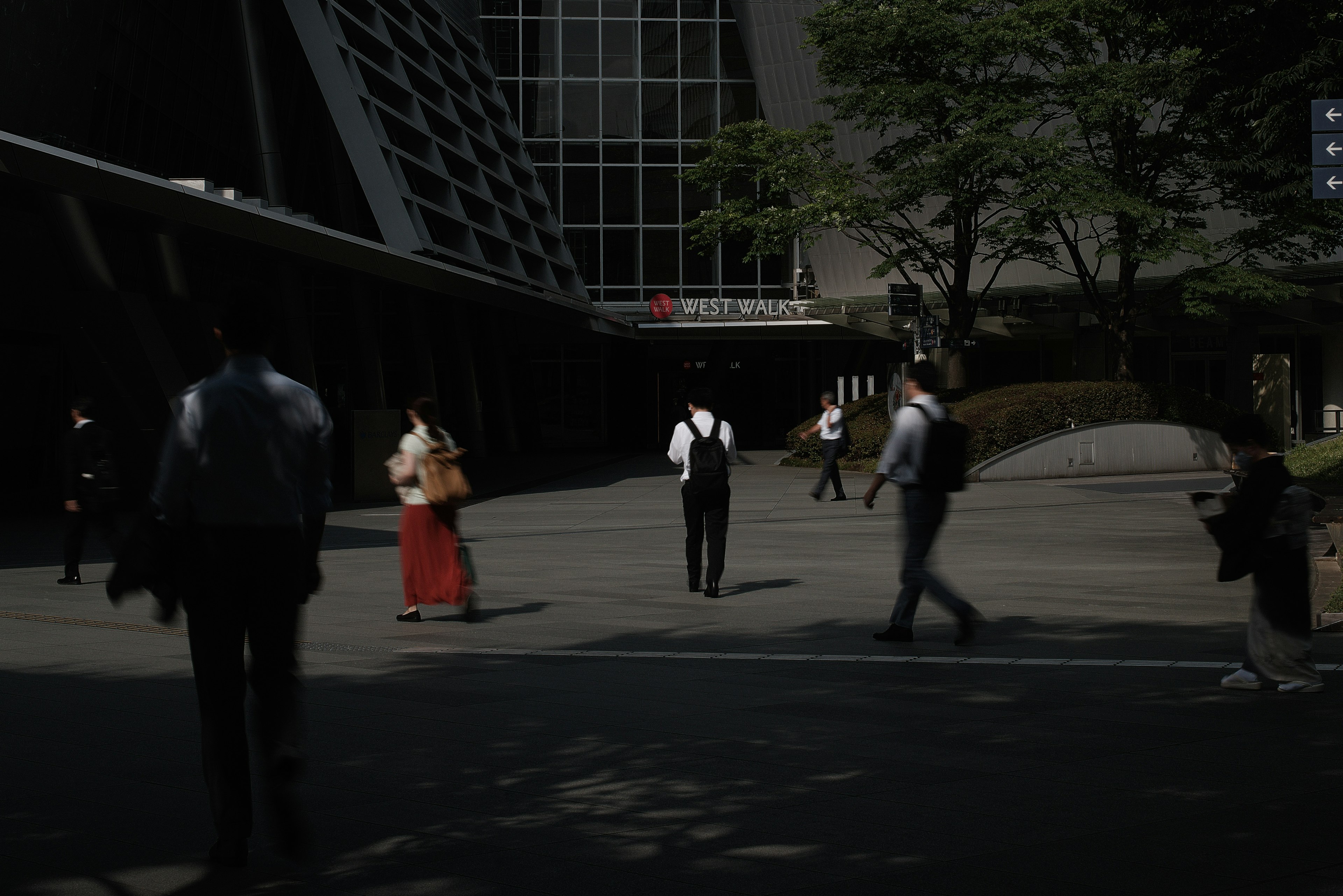 People in business suits walking in a modern urban setting with a woman in traditional attire