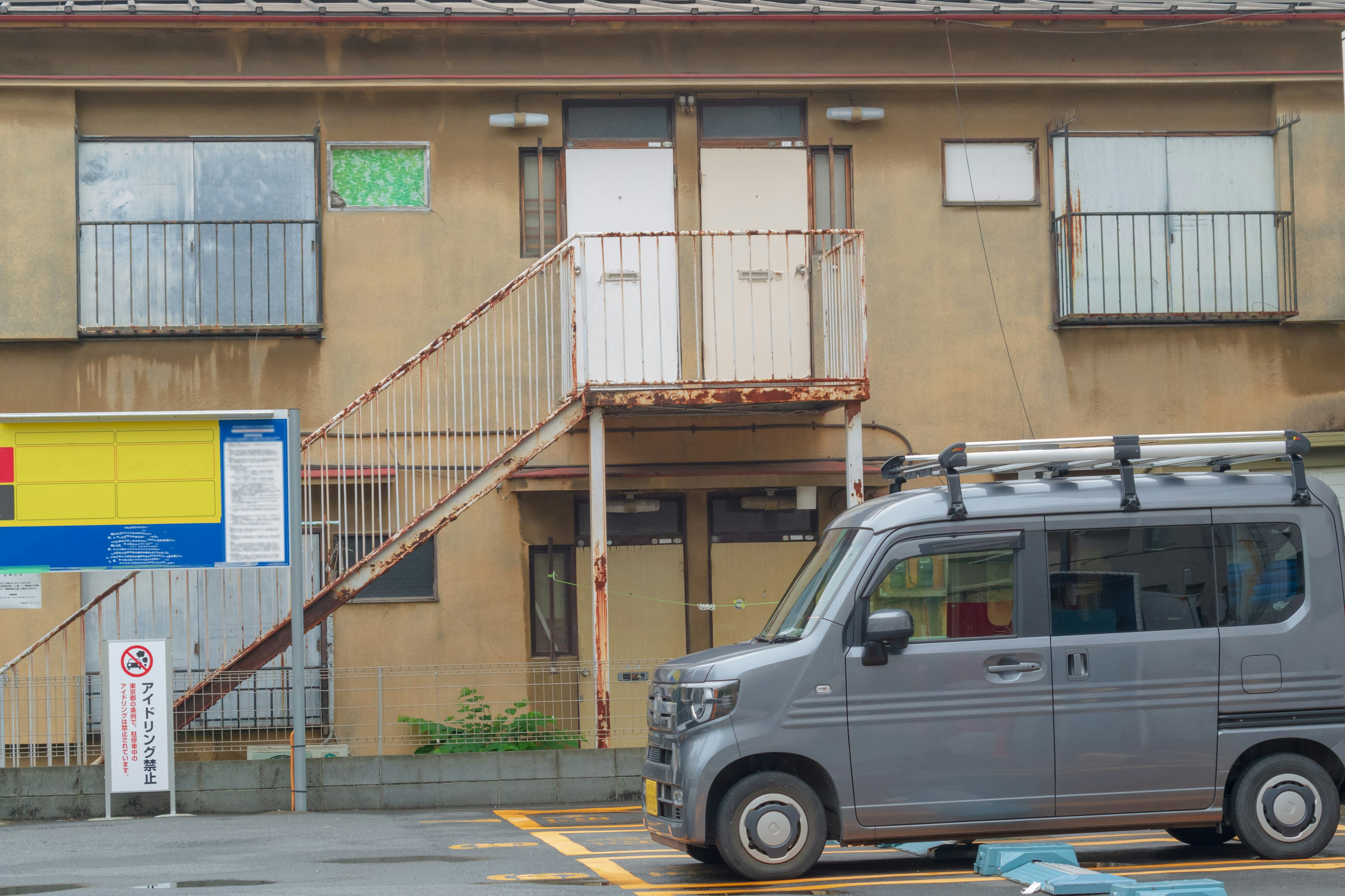 Exterior de un viejo edificio de apartamentos con un vehículo gris estacionado