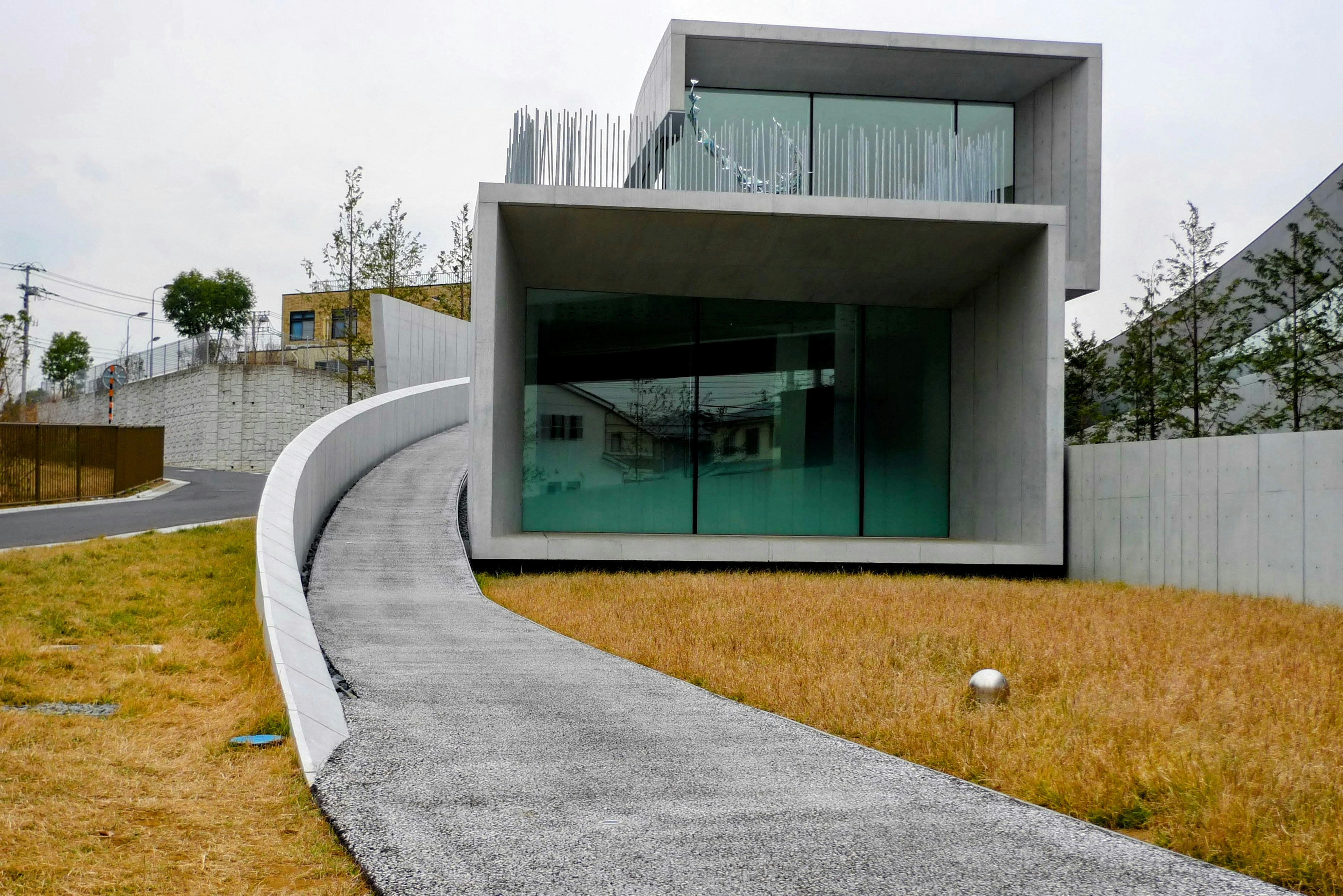 Modern concrete house with a curved driveway and grassy surroundings