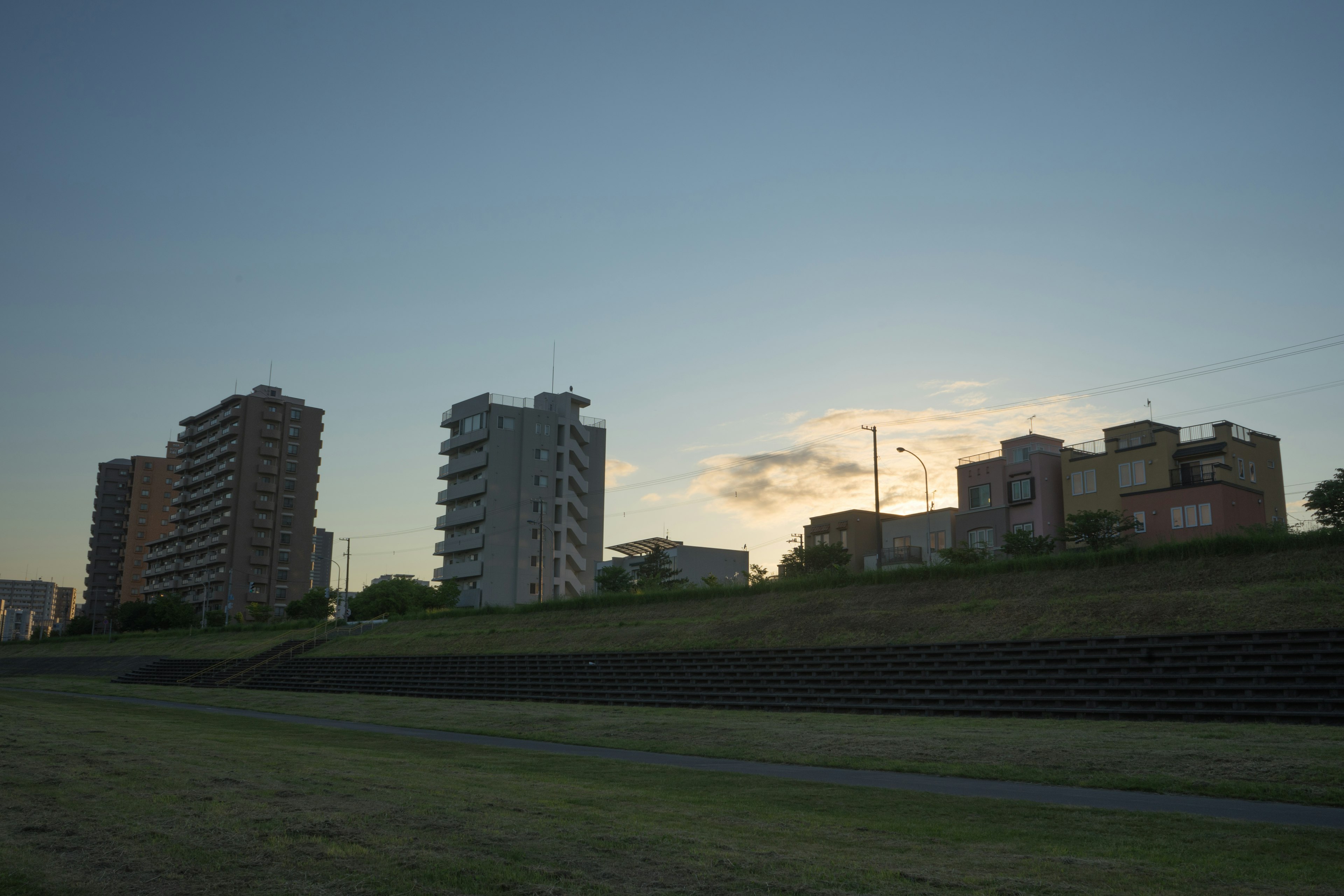 High-rise buildings against a sunset sky with green grass